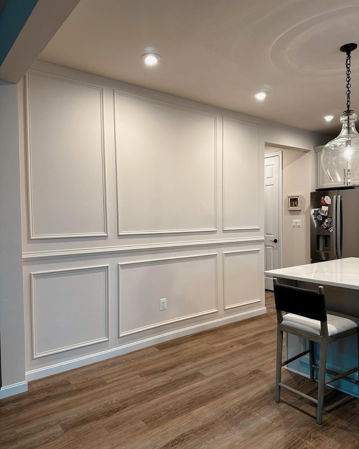 Monochromatic light gray wall with decorative panel molding and a matching chair rail.