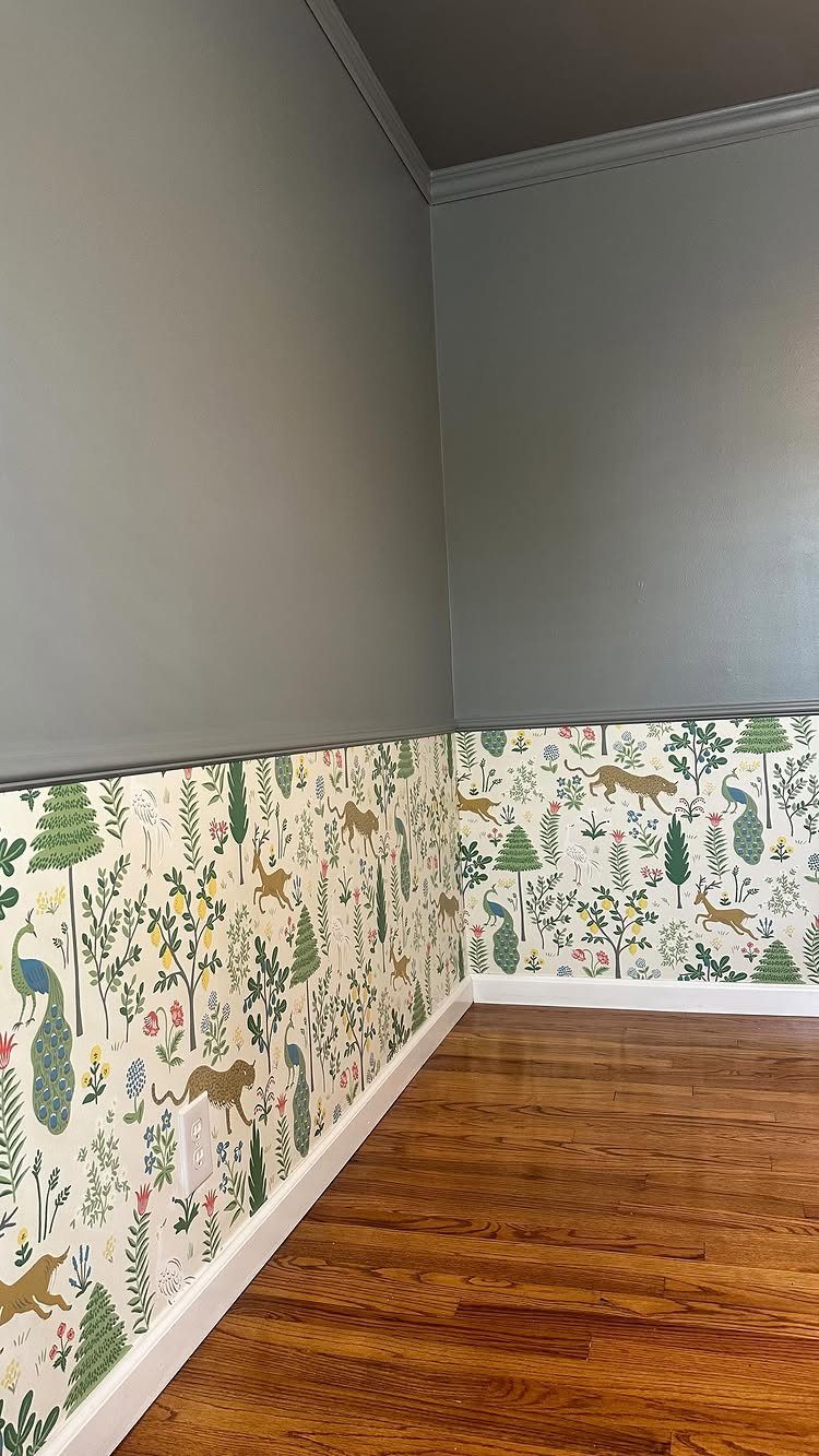 A room corner with grey painted upper walls and patterned wallpaper below a chair rail.