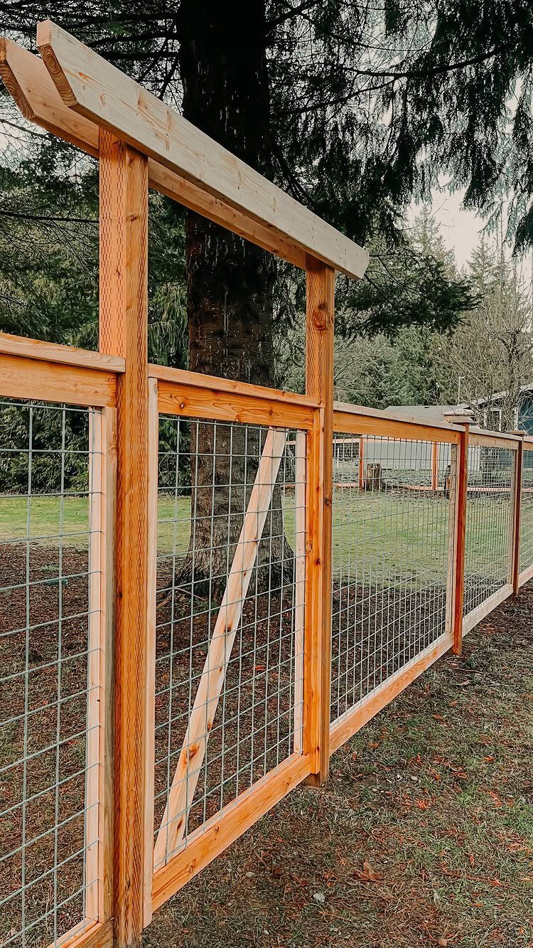 A wooden frame fence with wire mesh installed in a grassy backyard area with trees.