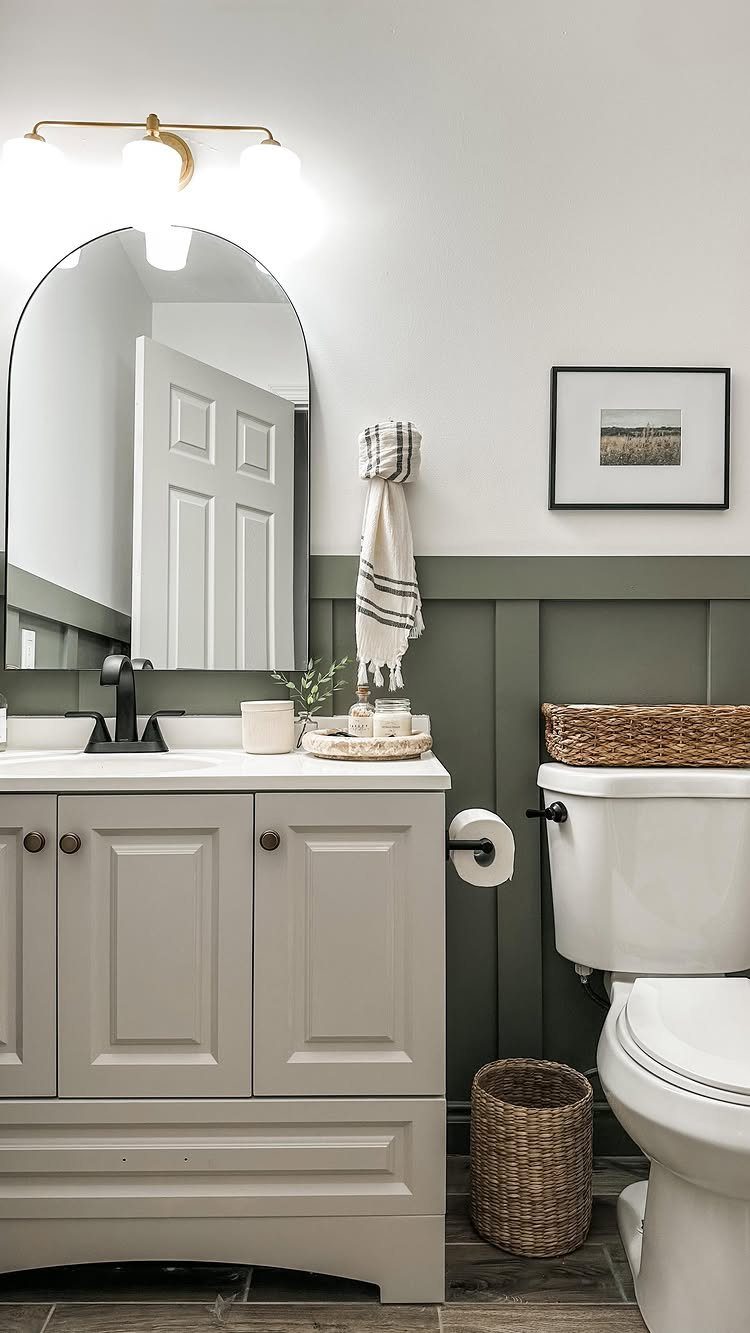 Sage green board and batten wainscoting installed on a bathroom wall behind a grey vanity.