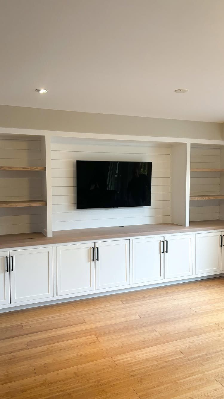 Built in Entertainment Center: 8 Design Ideas for Your Wall 8 White built-in entertainment center with wooden top, cabinets, and a mounted television on shiplap wall.