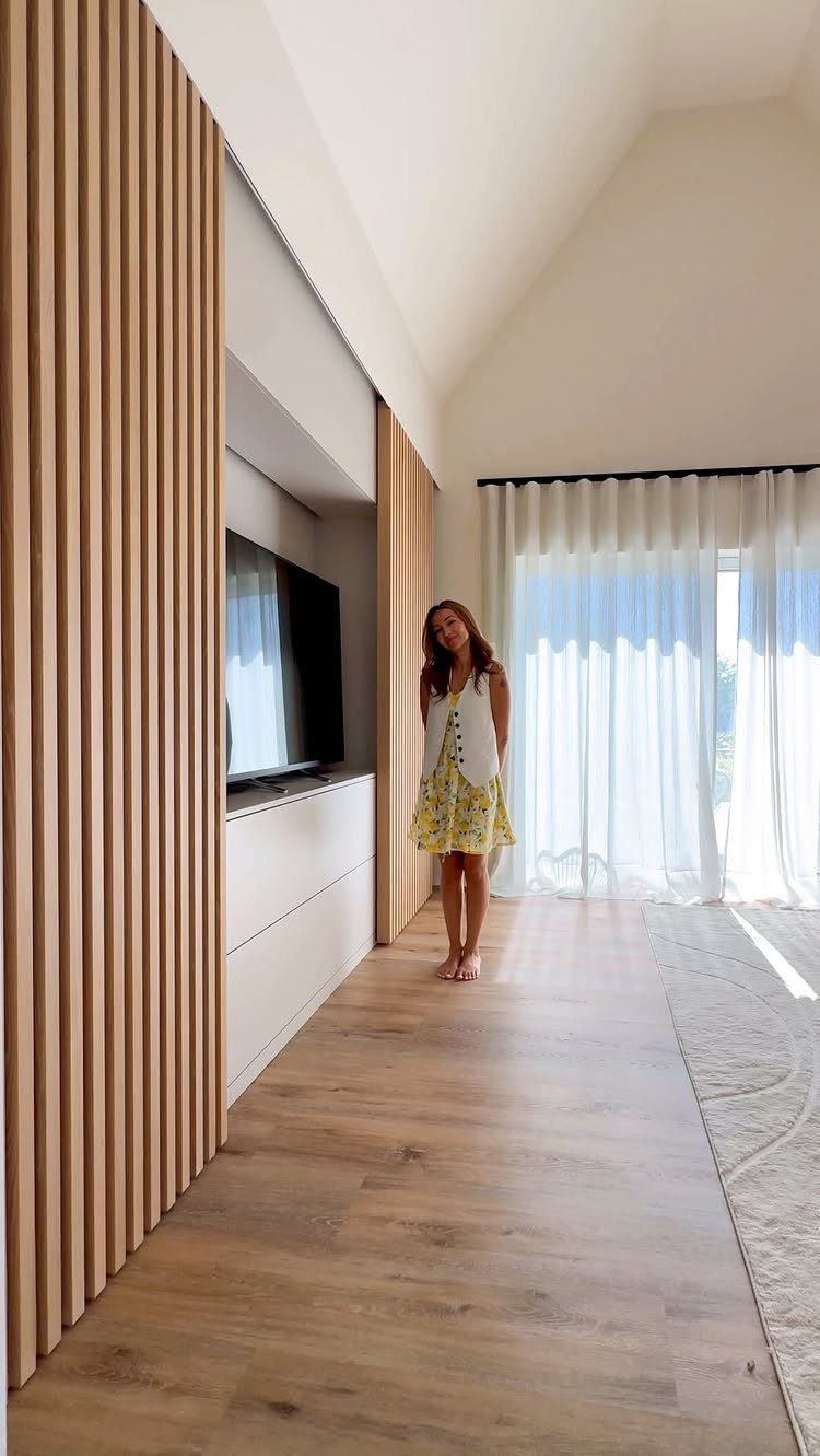 Built in Entertainment Center: 8 Design Ideas for Your Wall 7 A built-in entertainment center with wood slats and white cabinets in a bright living room.