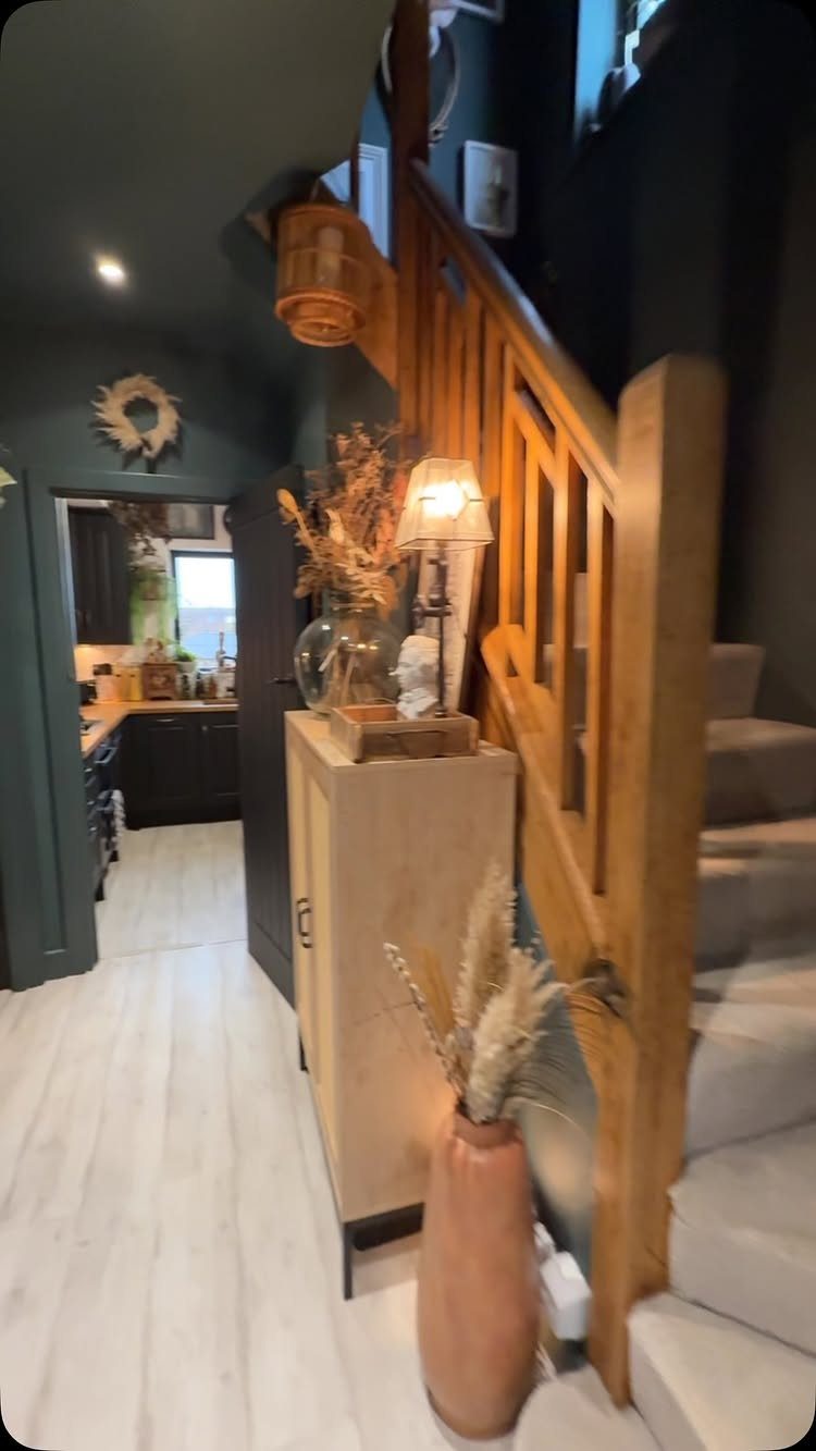 20 Dark Accent Wall Ideas to Try in Any Room 4 Light wooden furniture and stairs set against dark teal walls in a hallway.