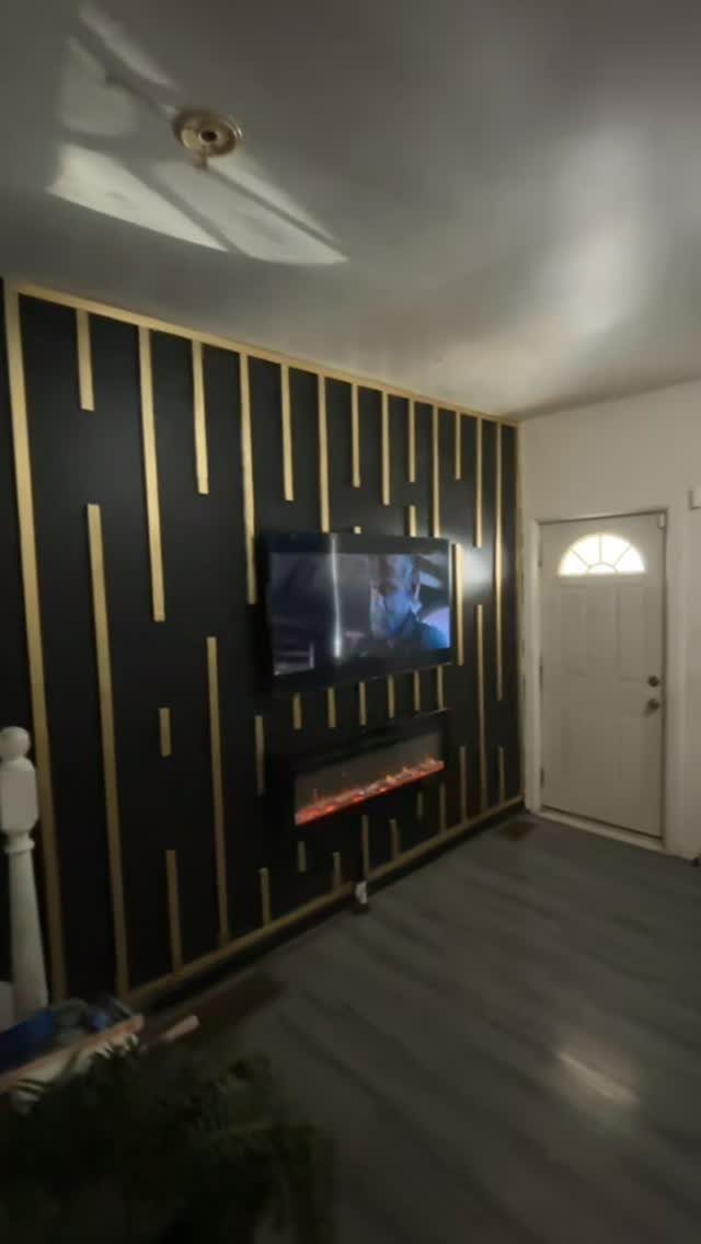 20 Dark Accent Wall Ideas to Try in Any Room 8 Dark accent wall with vertical gold metallic strips, a television, and an electric fireplace.