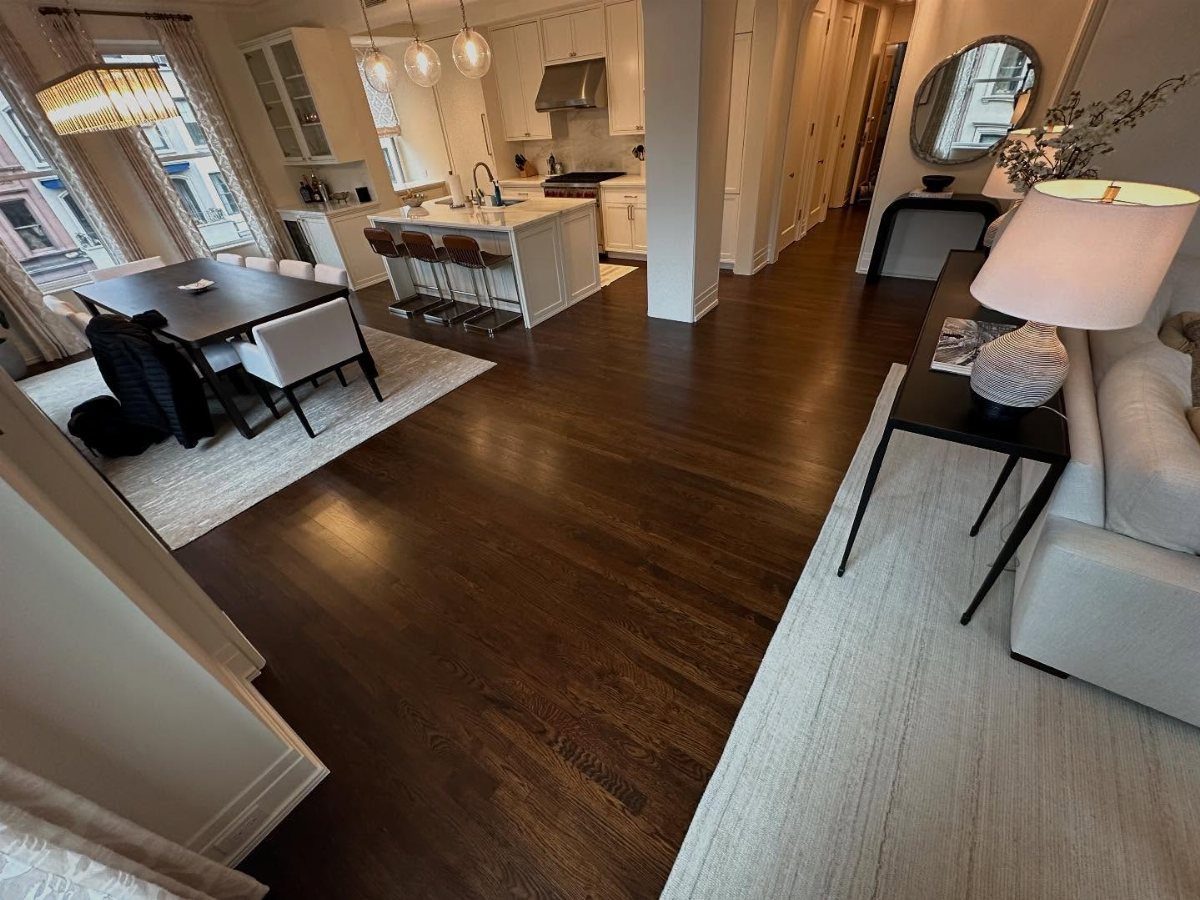 Dark hardwood flooring spanning across a modern open-concept living and dining room area.