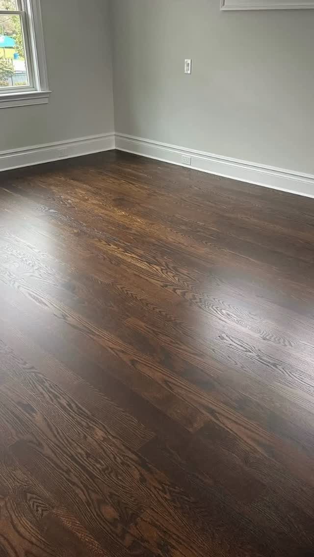Dark hardwood flooring with a subtle sheen installed in a room with grey walls.
