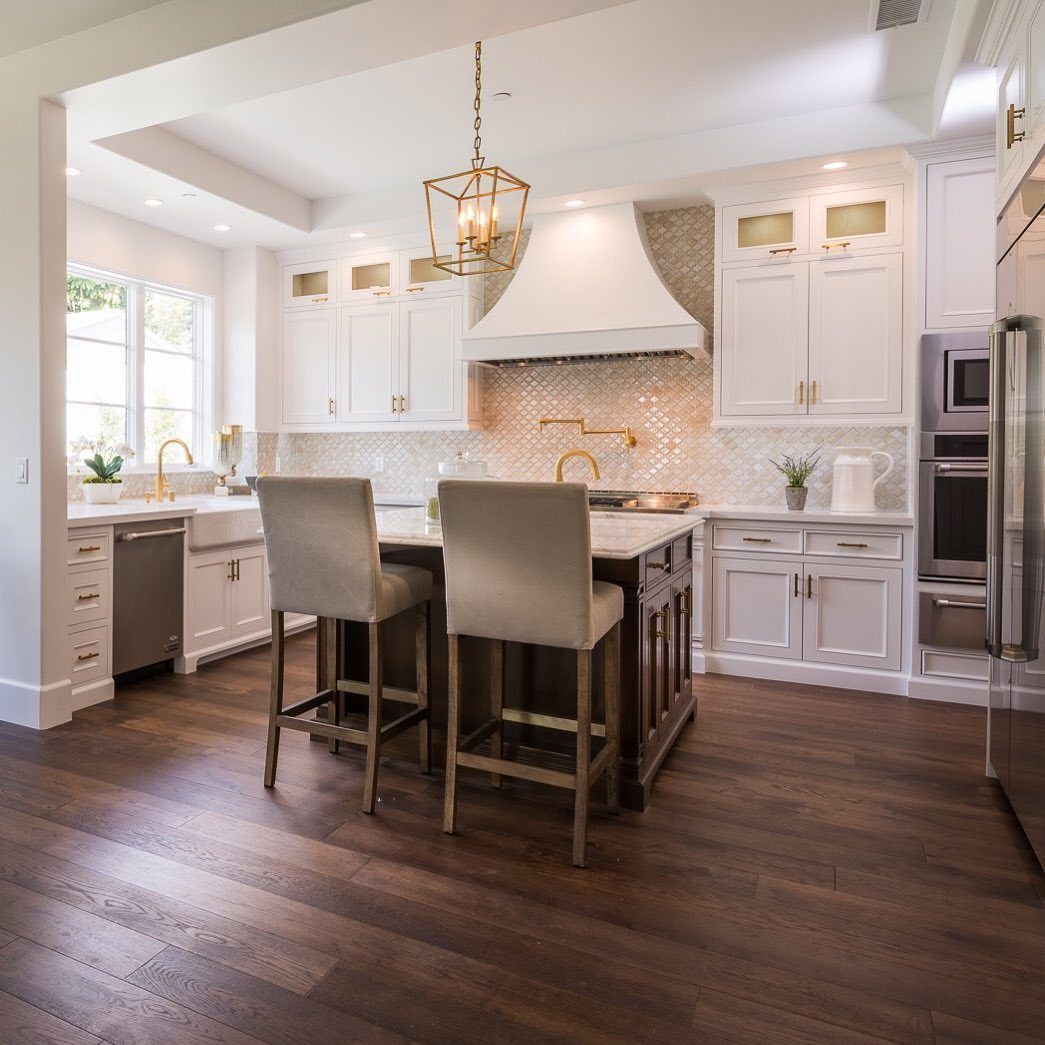 Dark hardwood floors in a bright, modern kitchen with white cabinets and a large island.