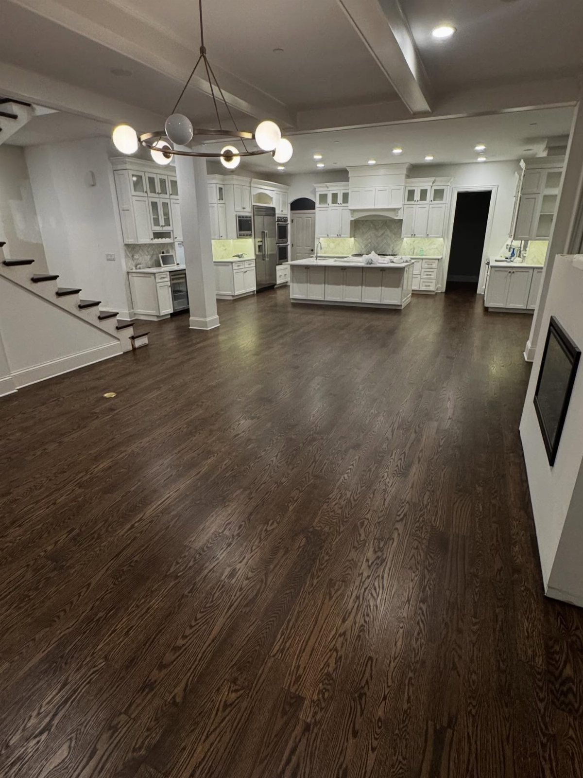 Dark walnut hardwood flooring stretching across a large, modern open-concept kitchen and living area.