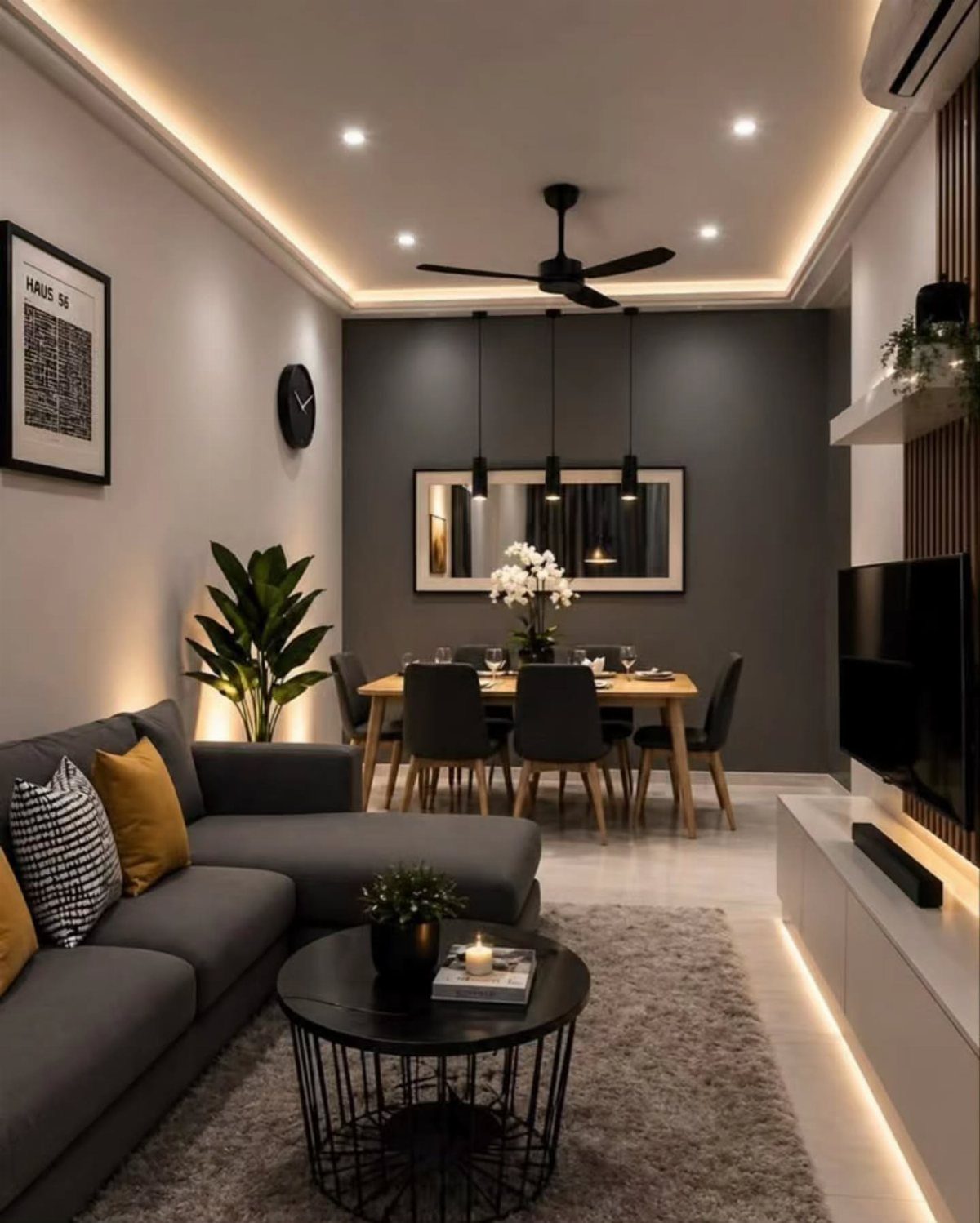 A dining room set against a dark charcoal grey accent wall with modern pendant lighting.