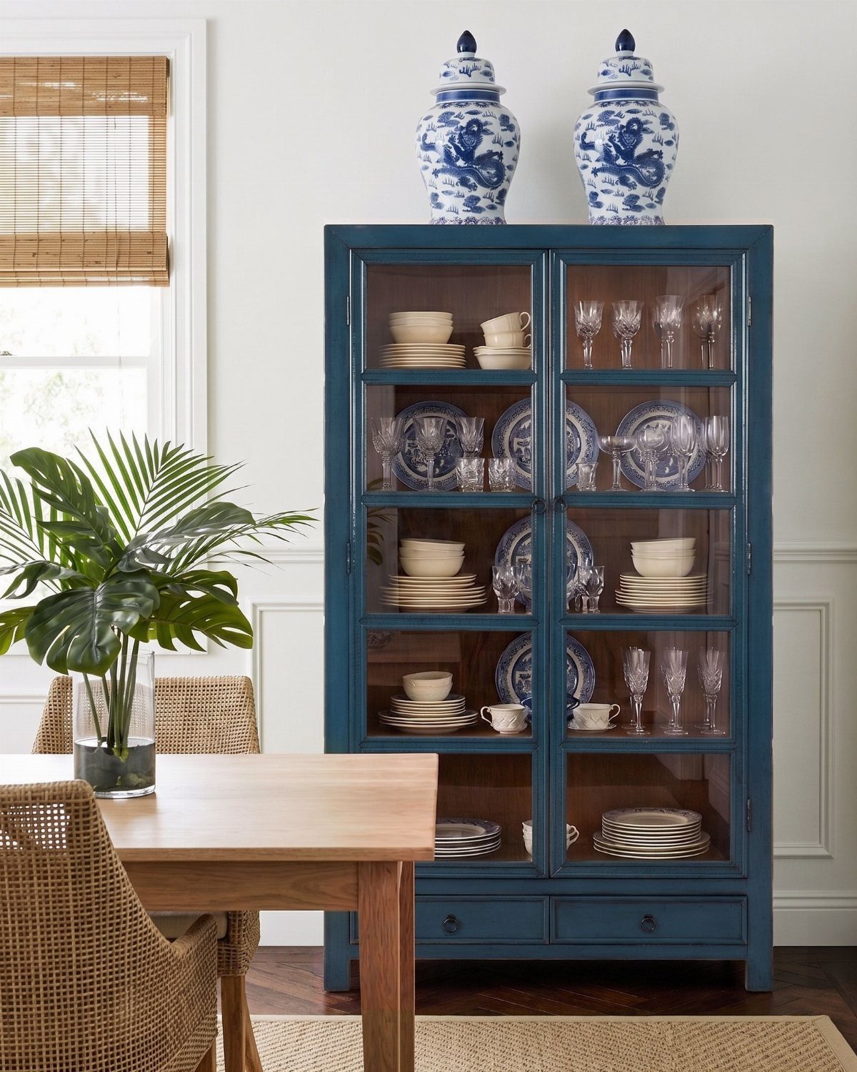 A teal blue glass-front display cabinet filled with blue and white ceramics and glassware.