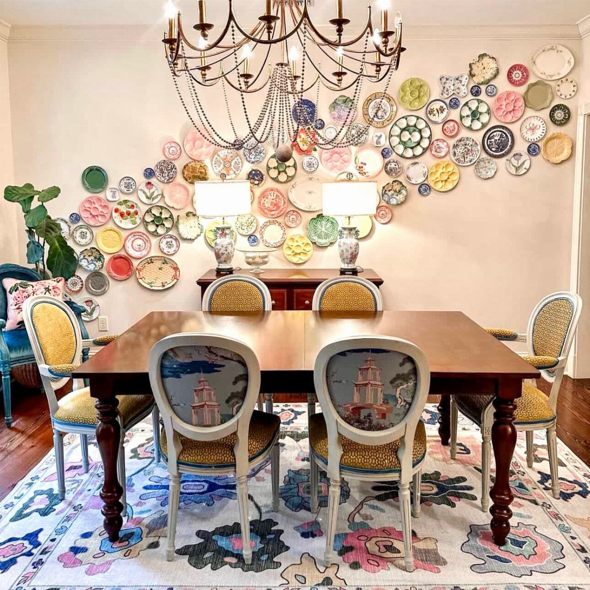 Colorful decorative plates arranged in a flowing pattern on a white dining room wall.