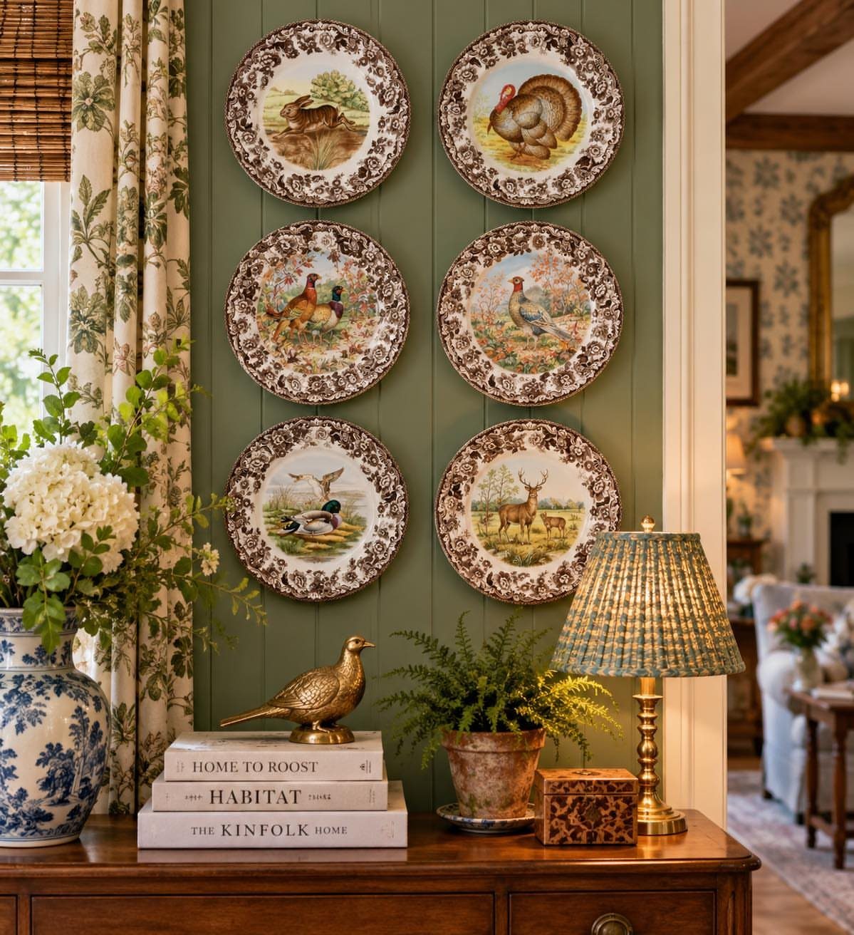 Six vintage plates with animal illustrations mounted on a green paneled wall above a wooden sideboard.