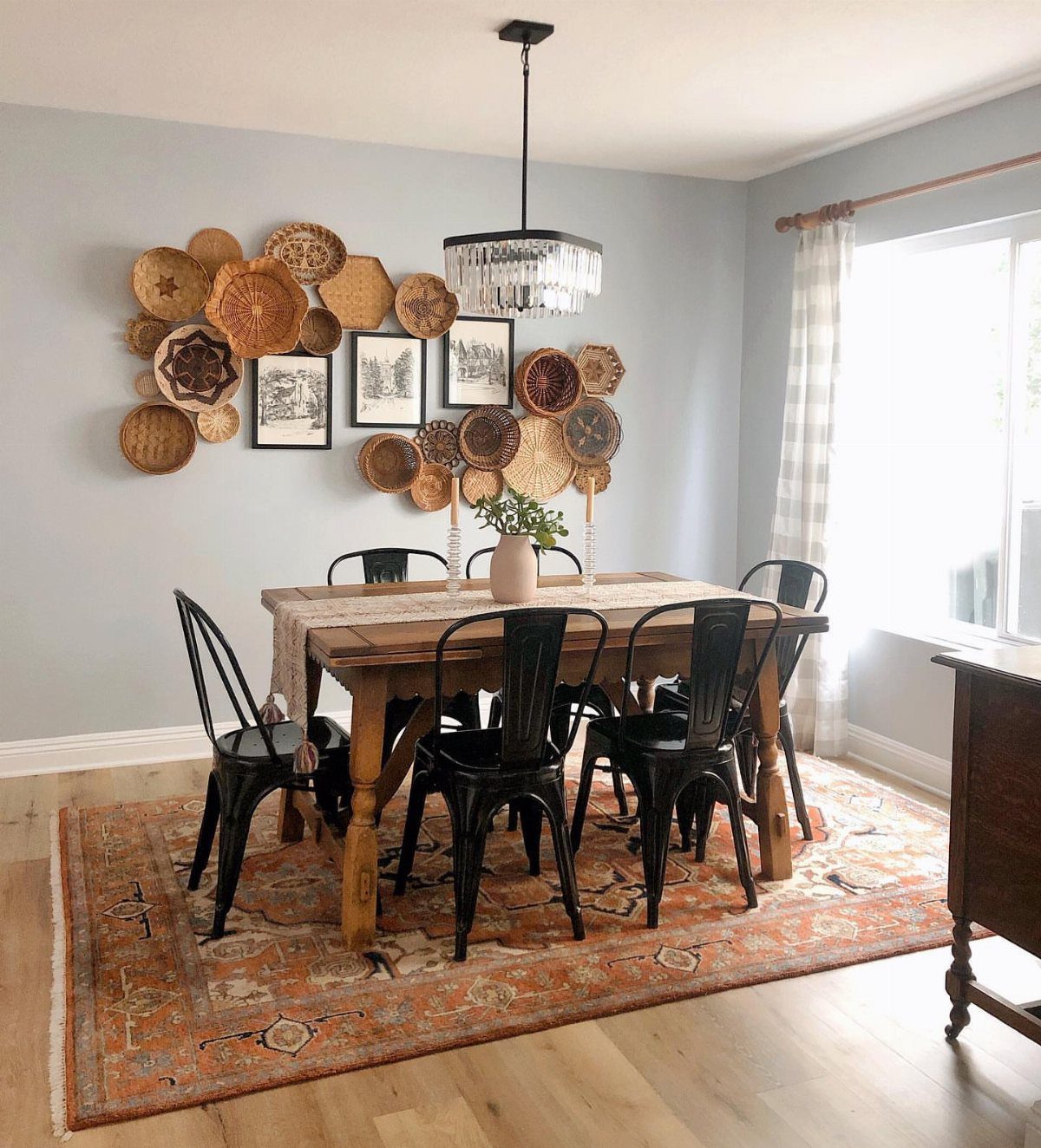 Woven wall baskets and framed art arranged on a light blue dining room wall.