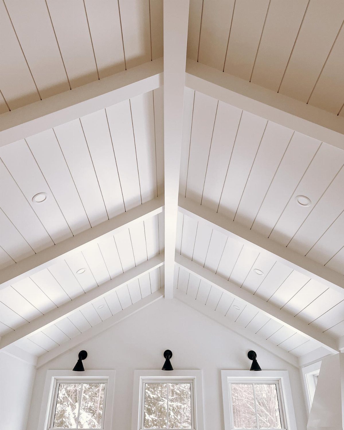 Floor to Ceiling Wall Paneling: 9 Rooms That Get It Right 2 White vaulted ceiling with wood paneling and large structural beams above three windows.