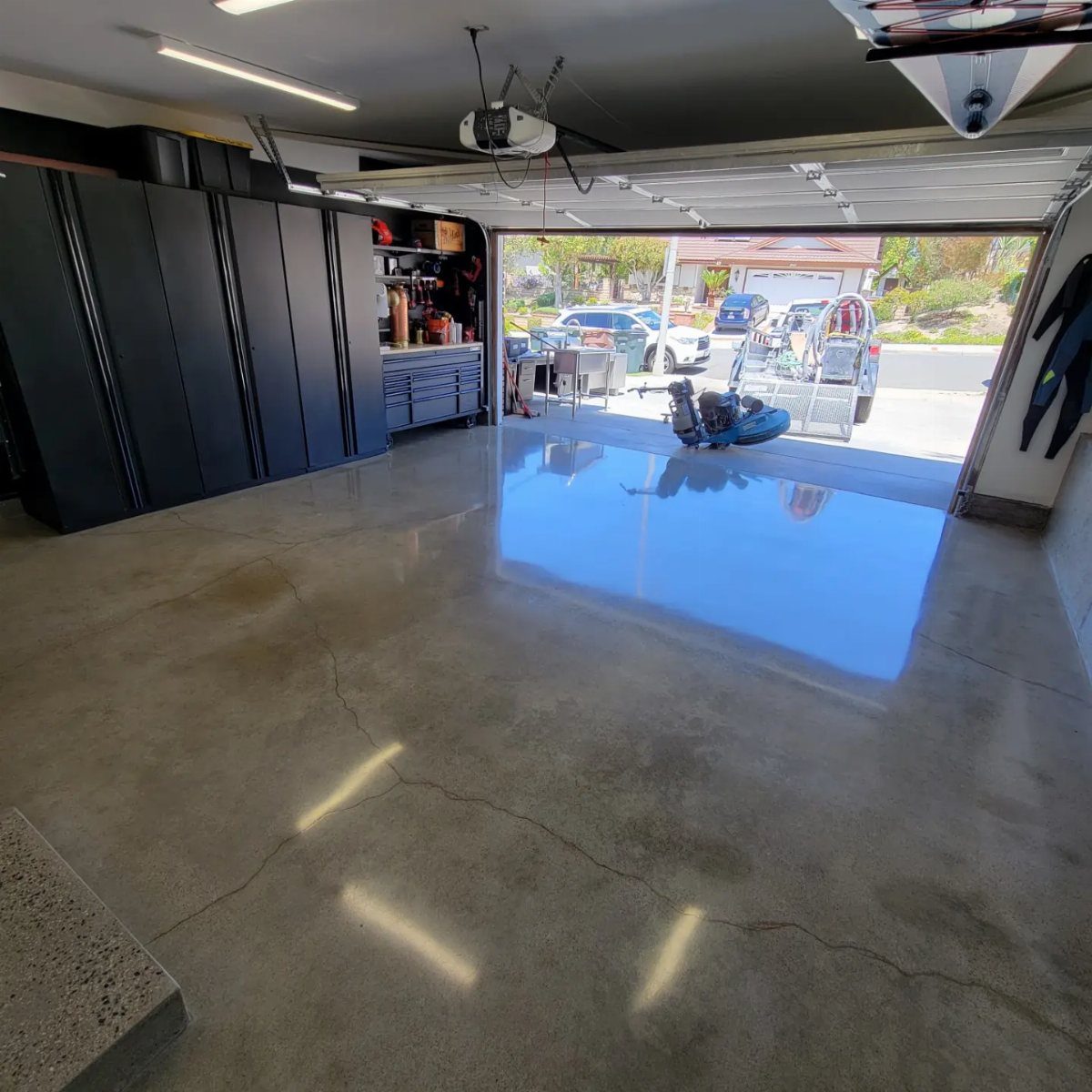 Polished concrete garage floor reflecting bright light from an open garage door.