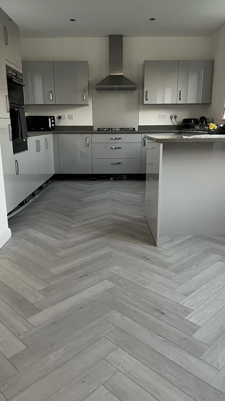 Light grey herringbone patterned wood-effect flooring in a modern kitchen setting.