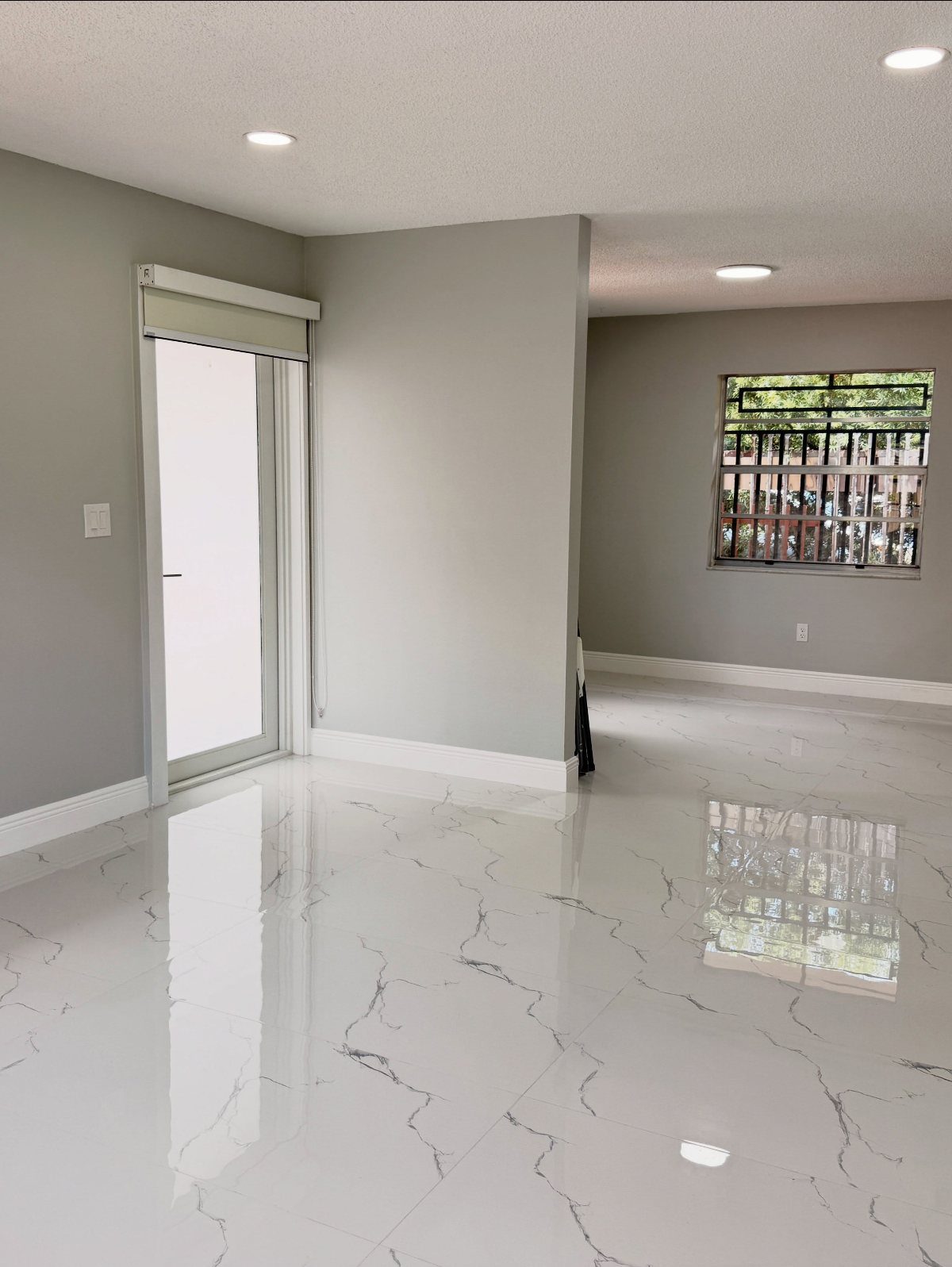 Polished white porcelain tiles with grey marble veining covering a bright, modern room floor.