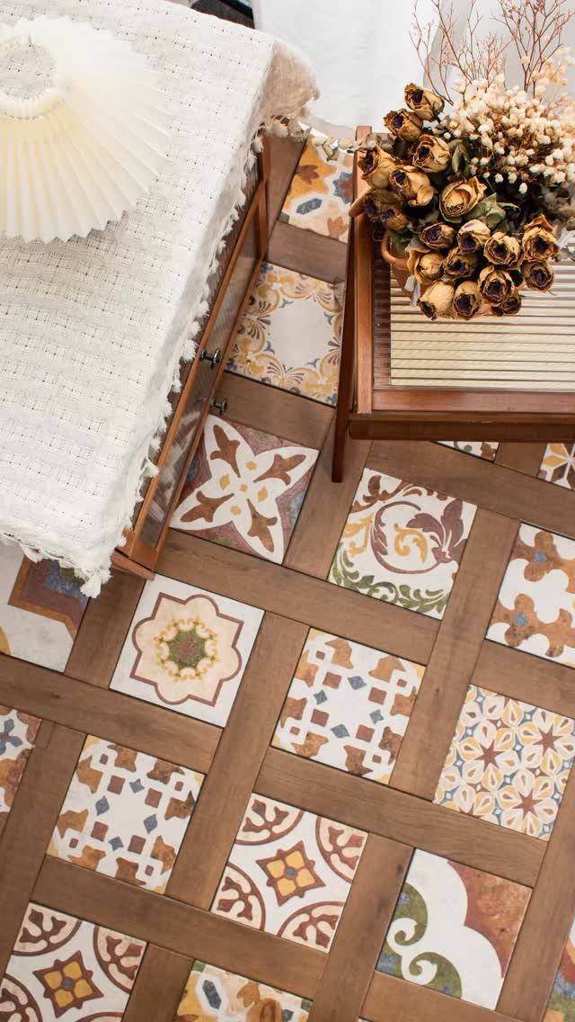 Flooring Trends 2026: 10 Ideas for Warmth, Texture, and Contrast 7 Patterned tiles with earthy motifs arranged in a dark wood lattice floor pattern.