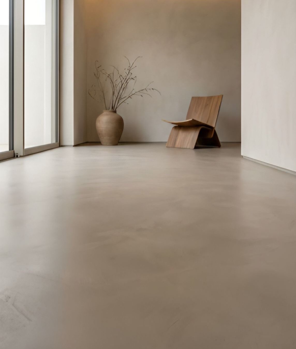 Flooring Trends 2026: 10 Ideas for Warmth, Texture, and Contrast 9 Smooth beige microcement flooring in a minimalist room with a wooden chair and ceramic vase.
