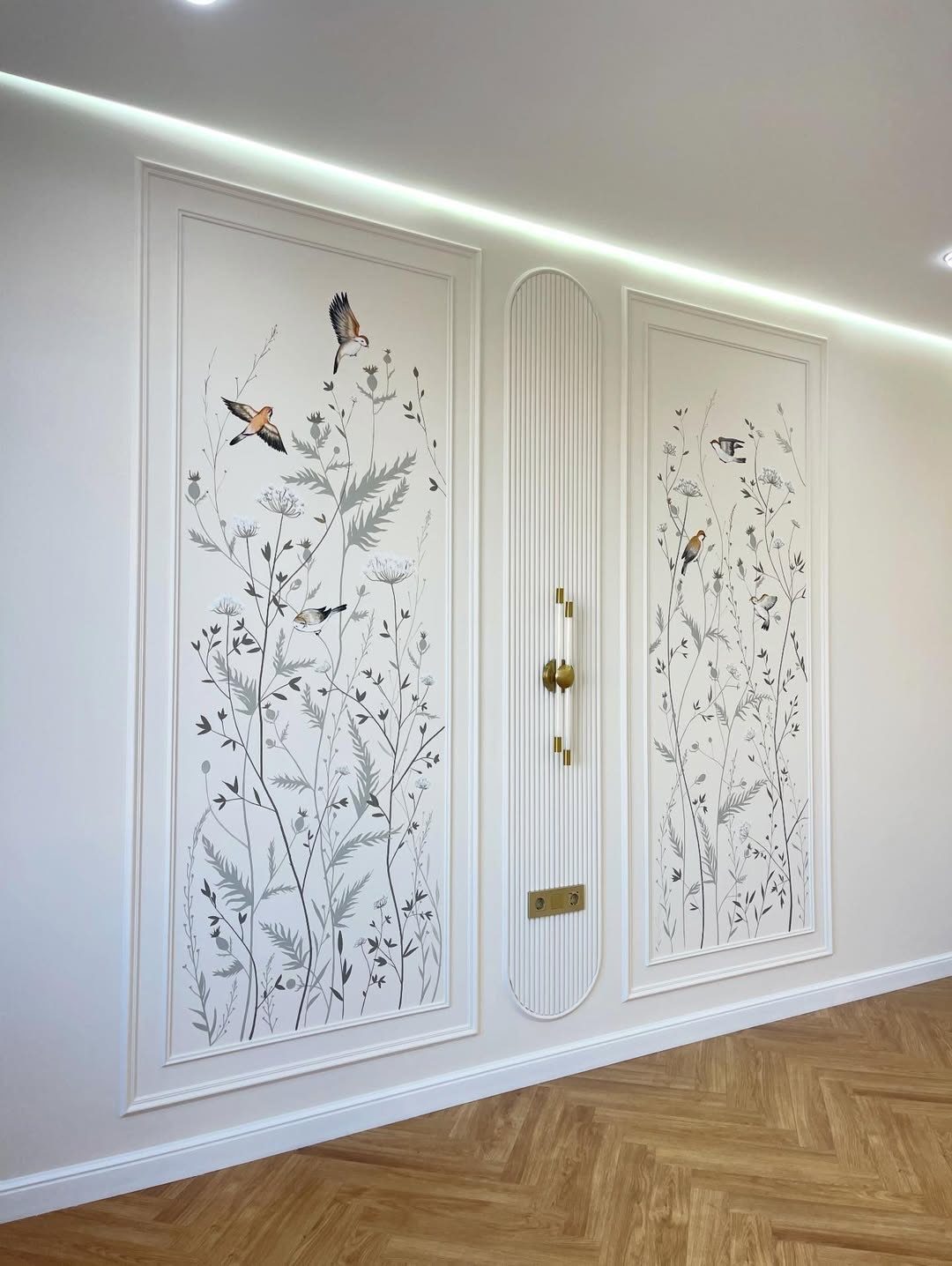 White wall molding panels with botanical bird illustrations and a fluted central panel on a herringbone floor.