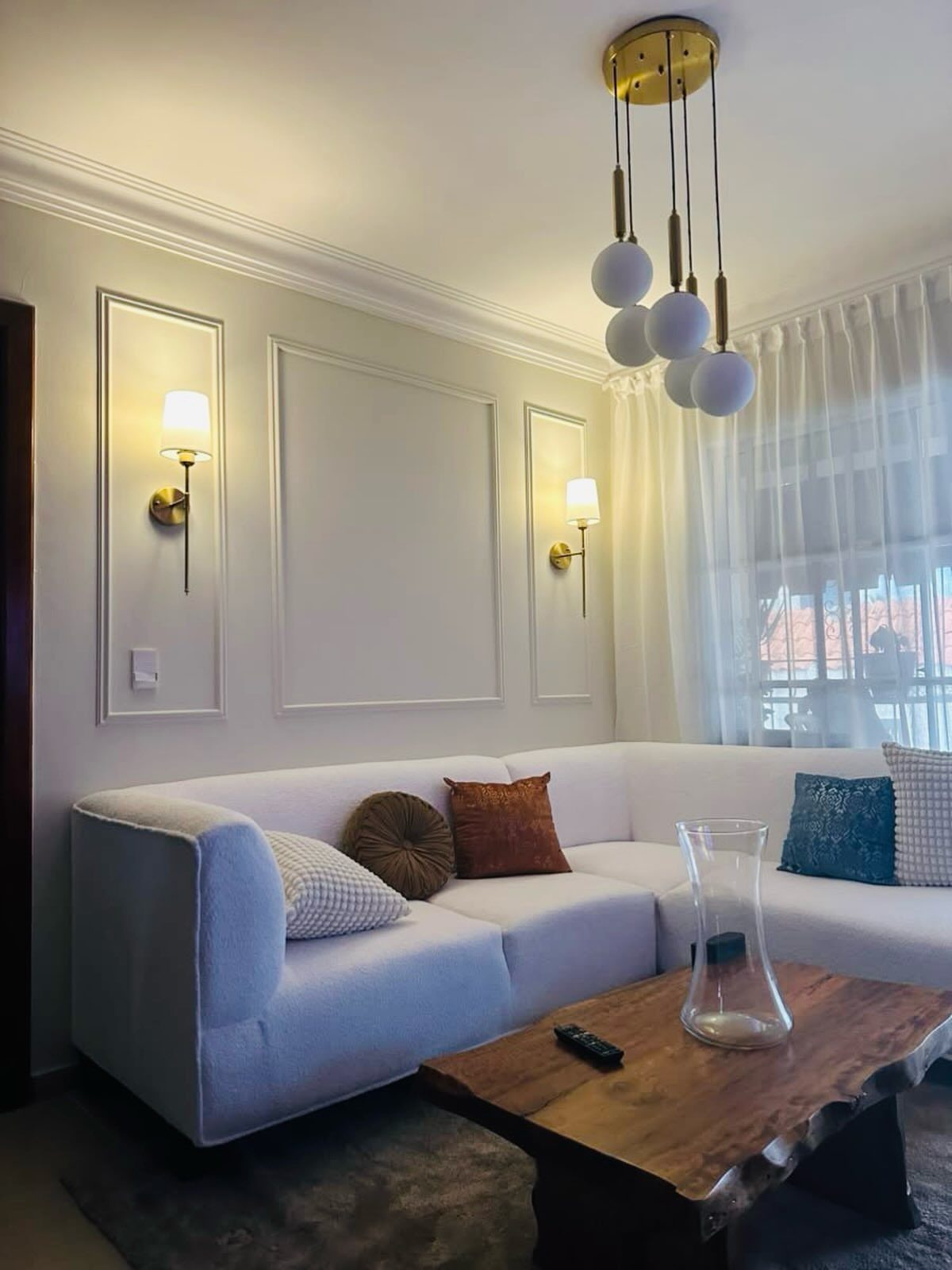 White sectional sofa and wooden coffee table in a room with decorative wall moulding.