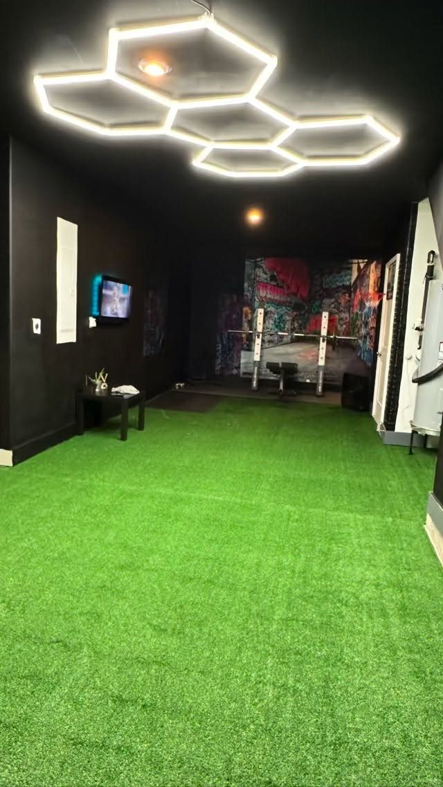 Green artificial turf covering the floor of a dark room with hexagonal LED lights.