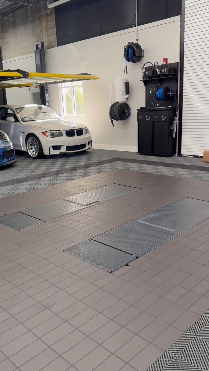 Grey interlocking tiles covering a garage floor with a white car parked in the background.