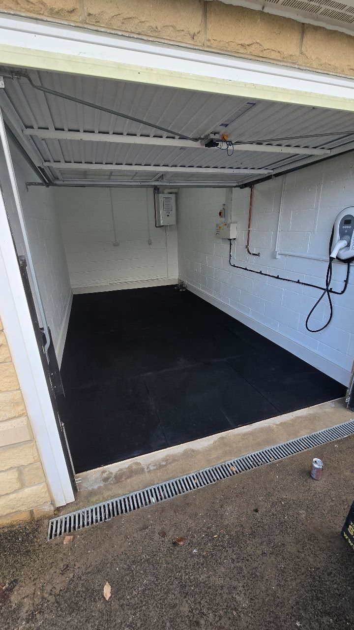 A dark black garage floor covering the ground inside a white walled garage space.