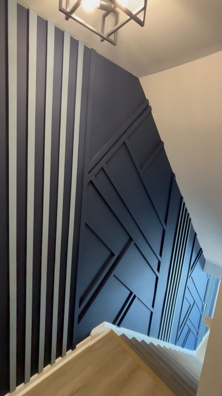 Geometric Accent Wall: 11 Ideas in Wood, Paint, and Light 4 Dark navy blue geometric accent wall with raised wooden slats in a staircase area.