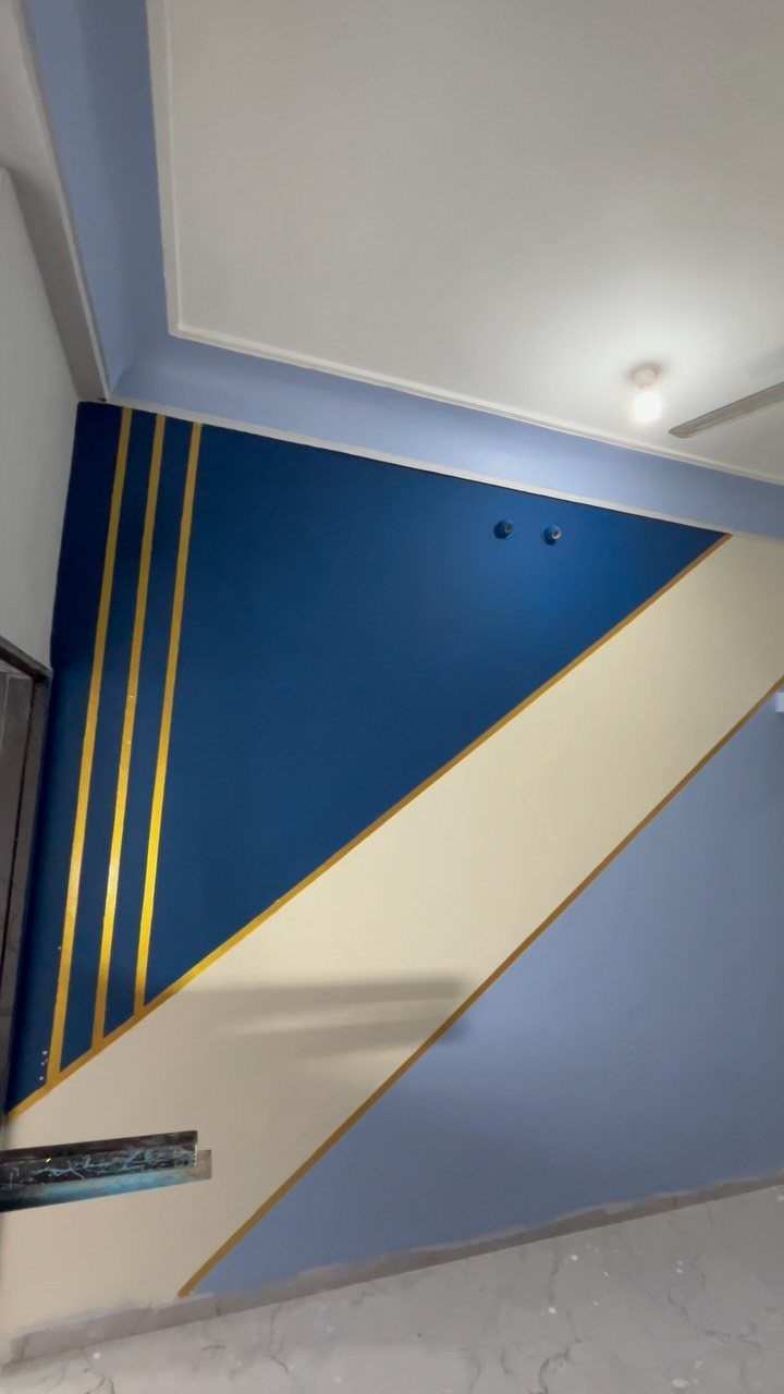 Geometric Accent Wall: 11 Ideas in Wood, Paint, and Light 7 Geometric wall design with blue, cream, and light blue sections separated by gold stripes.