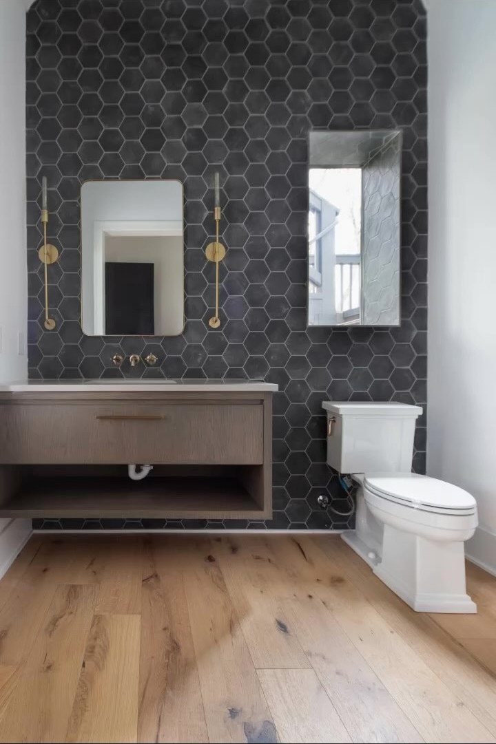 12 Half Bath Accent Wall Ideas That Work in Tight Spaces 6 Dark grey hexagonal tiles cover the accent wall in a modern bathroom with wooden floors.