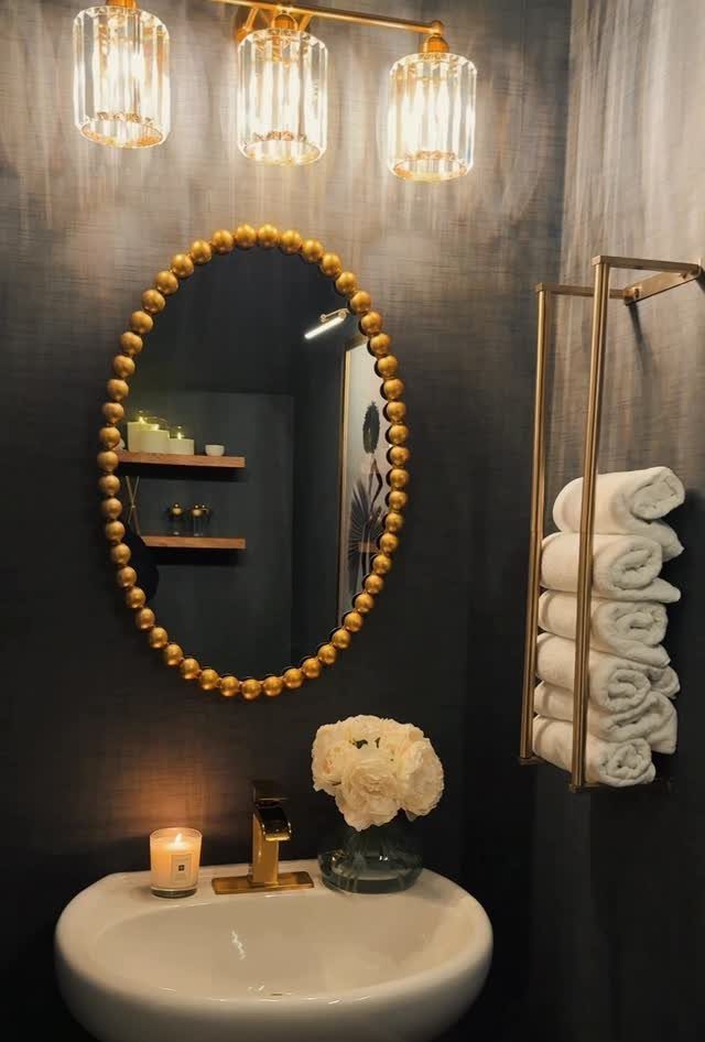 12 Half Bath Accent Wall Ideas That Work in Tight Spaces 10 Gold beaded oval mirror hanging on a dark textured bathroom wall above a white sink.