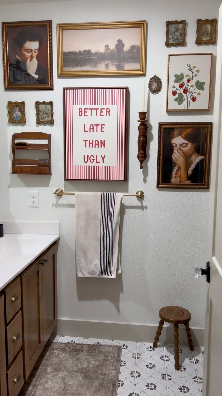 12 Half Bath Accent Wall Ideas That Work in Tight Spaces 3 Framed art pieces and a striped sign arranged in a gallery wall on a white bathroom wall.