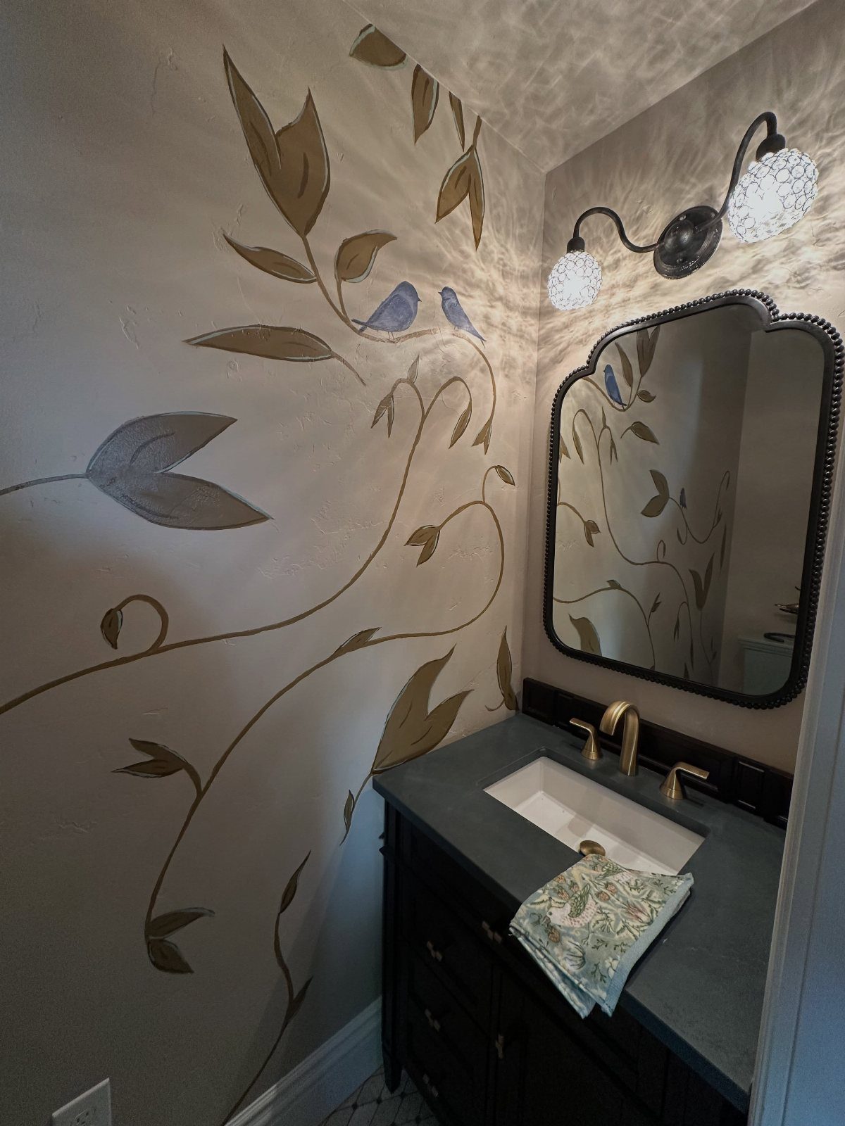 12 Half Bath Accent Wall Ideas That Work in Tight Spaces 8 A bathroom wall featuring a large painted mural of leaves and birds above a dark vanity.