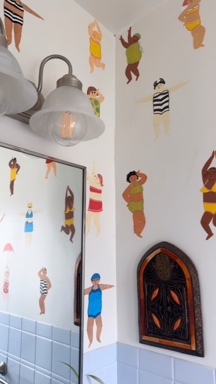 12 Half Bath Accent Wall Ideas That Work in Tight Spaces 12 Cartoon swimsuit decals decorating a white bathroom wall above light blue tiles.