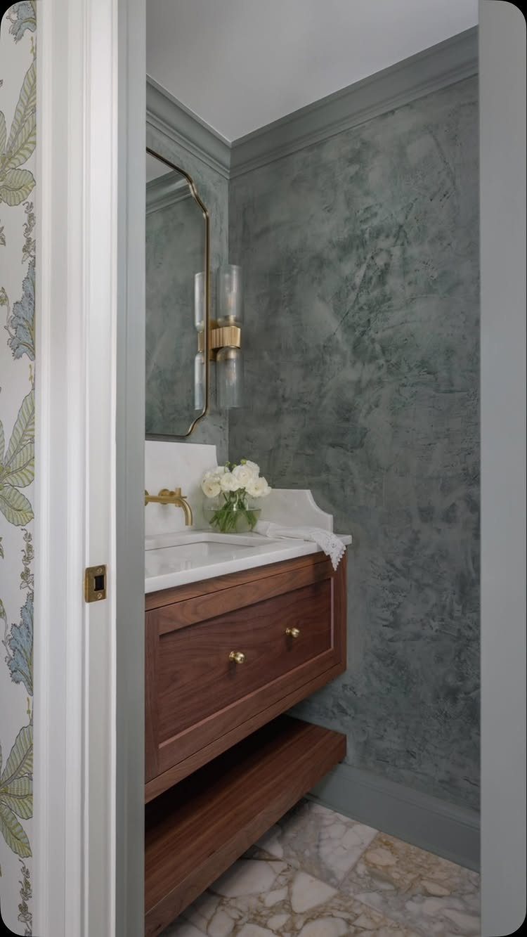 12 Half Bath Accent Wall Ideas That Work in Tight Spaces 5 A textured blue-grey bathroom wall featuring a gold wall sconce and wooden vanity.