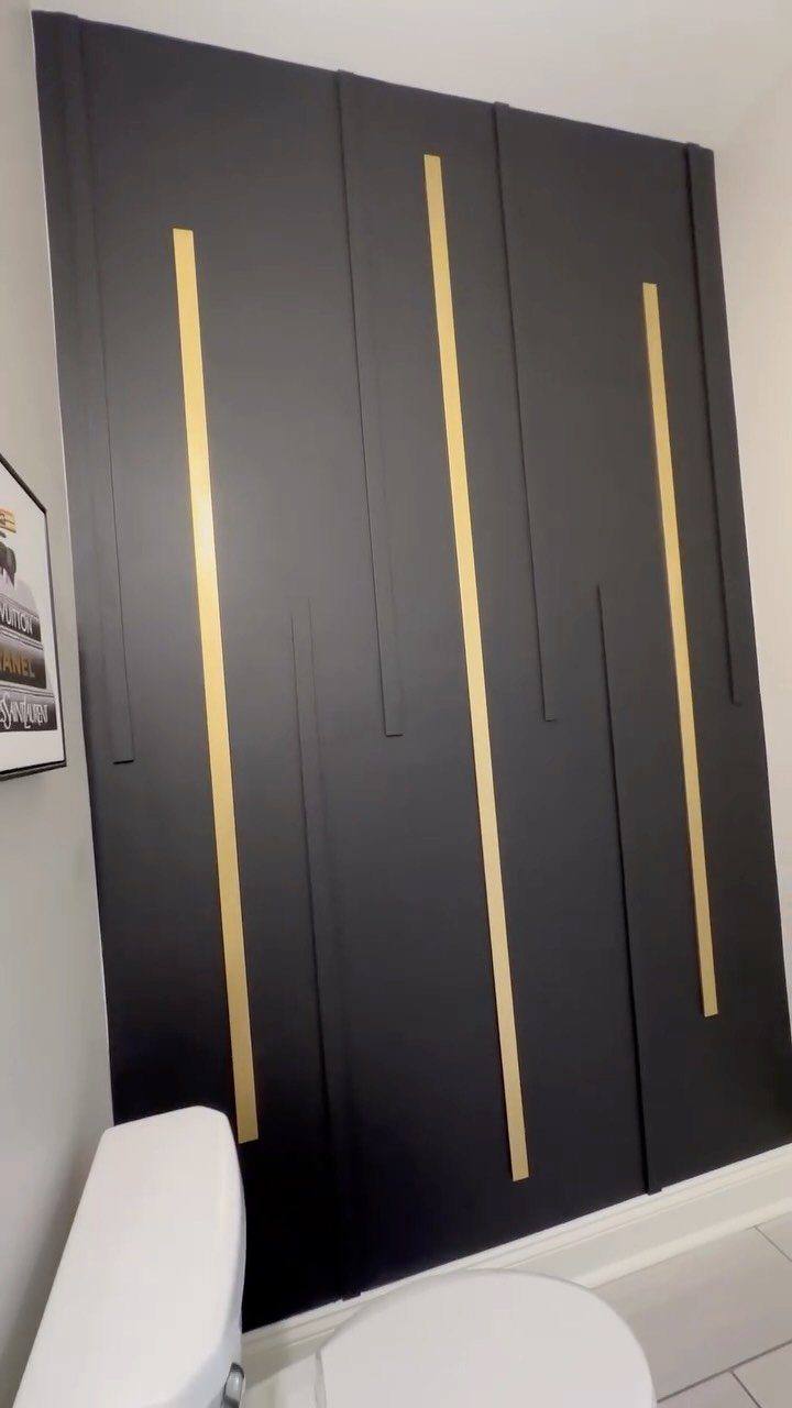 12 Half Bath Accent Wall Ideas That Work in Tight Spaces 11 Black accent wall with vertical wooden slats and gold metallic strips in a bathroom.