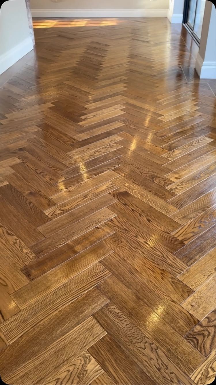 10 Hardwood Flooring Ideas for Every Room Style 11 Polished medium-brown hardwood flooring laid in a decorative herringbone pattern.
