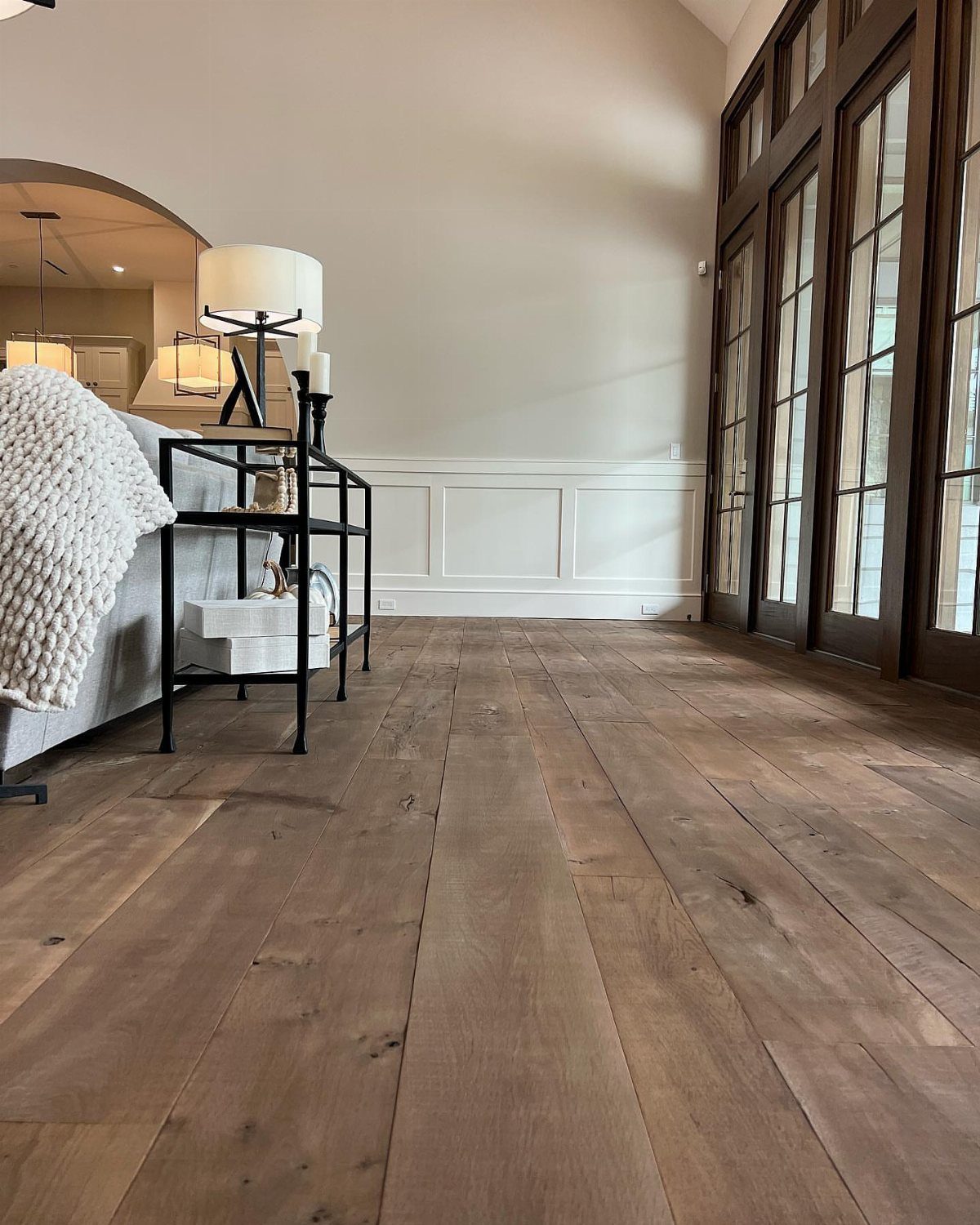 10 Hardwood Flooring Ideas for Every Room Style 2 Wide rustic hardwood planks with natural grain patterns in a bright, modern living space.