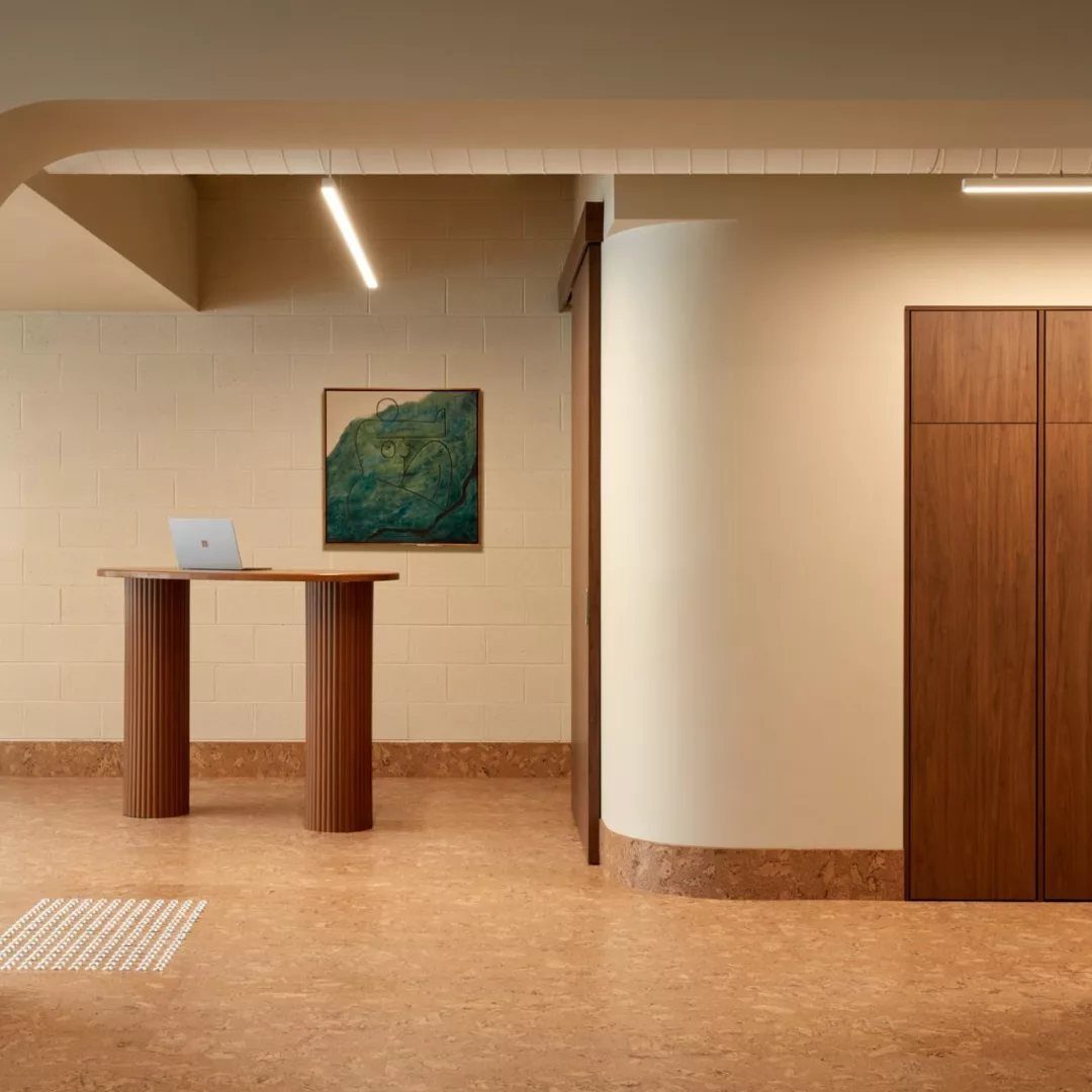 Tan cork flooring in a minimalist room with a wooden table and tall cabinets.
