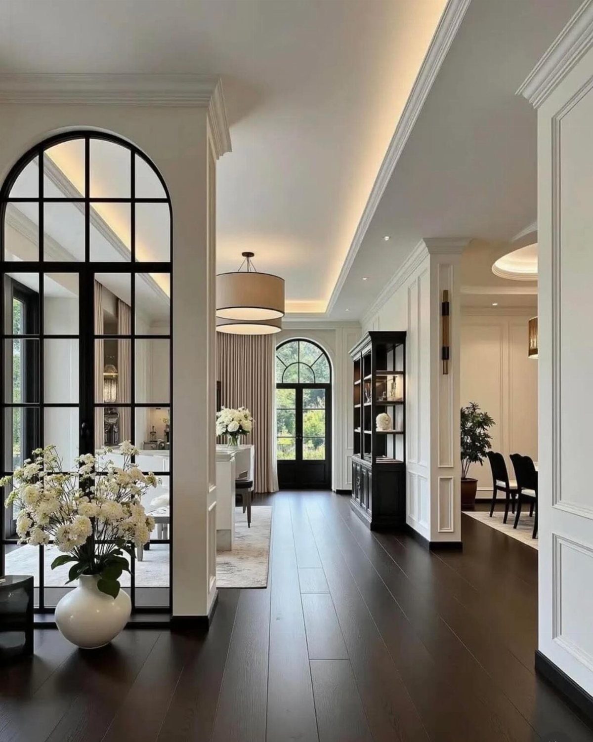 Dark polished hardwood flooring stretching through a bright, modern hallway with arched glass doors.