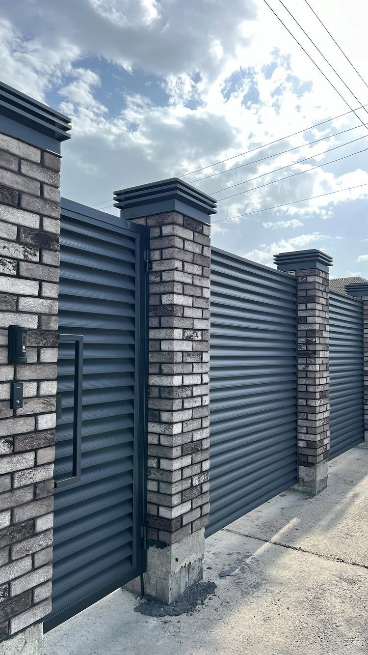 Horizontal Slat Fence: 8 Designs for Modern Backyards 5 Dark grey horizontal slat fence panels installed between light brick pillars outdoors.