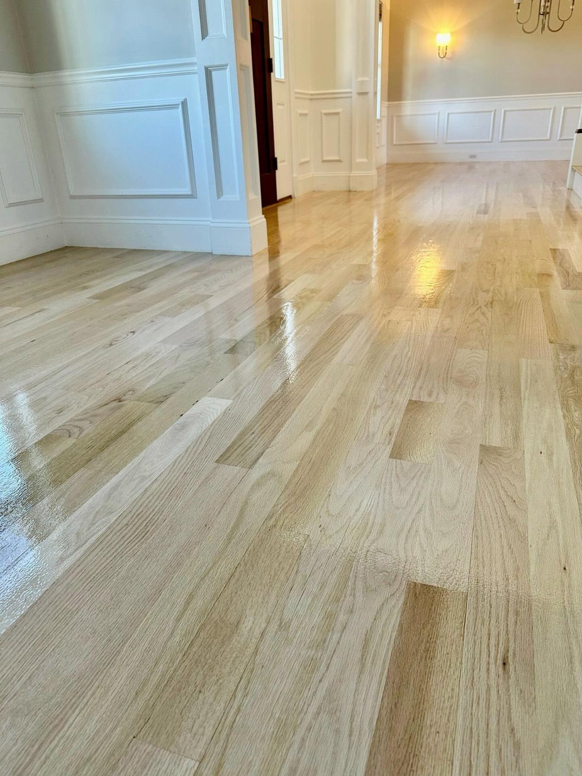 Light oak wood flooring with a glossy finish in a bright hallway.