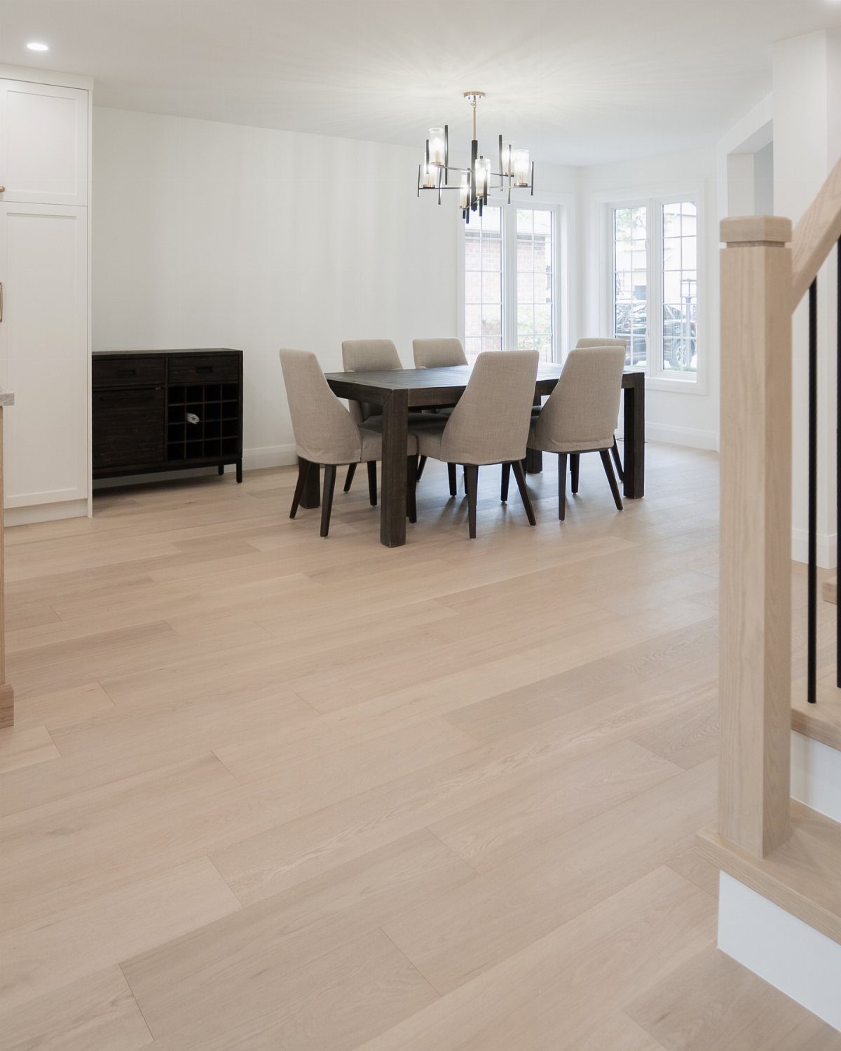 Light oak wood flooring in a bright dining room with a dark wooden table.