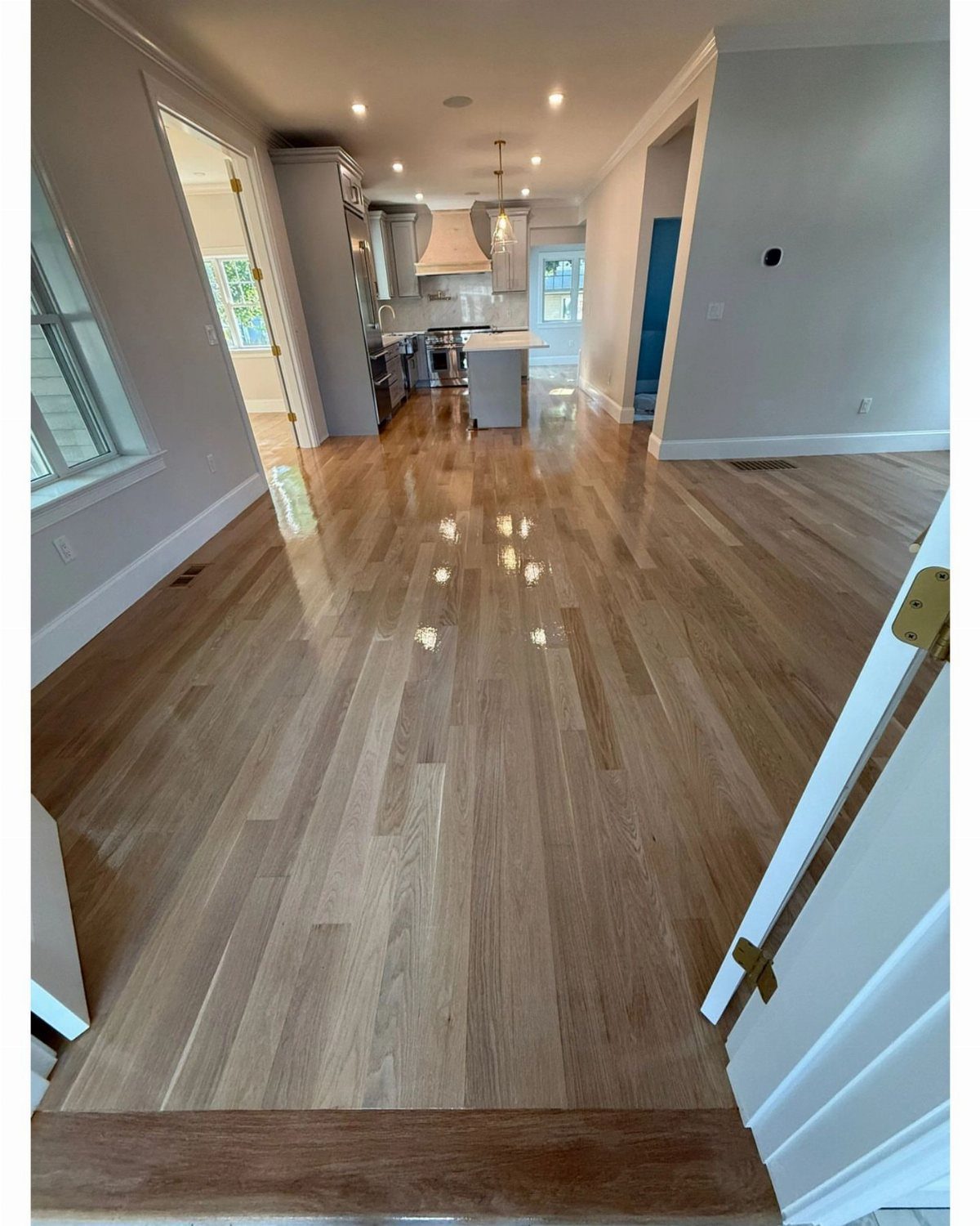 Light Wood Flooring: 10 Ideas That Actually Work 9 Light wood flooring stretching through a modern open-concept home interior towards a kitchen.