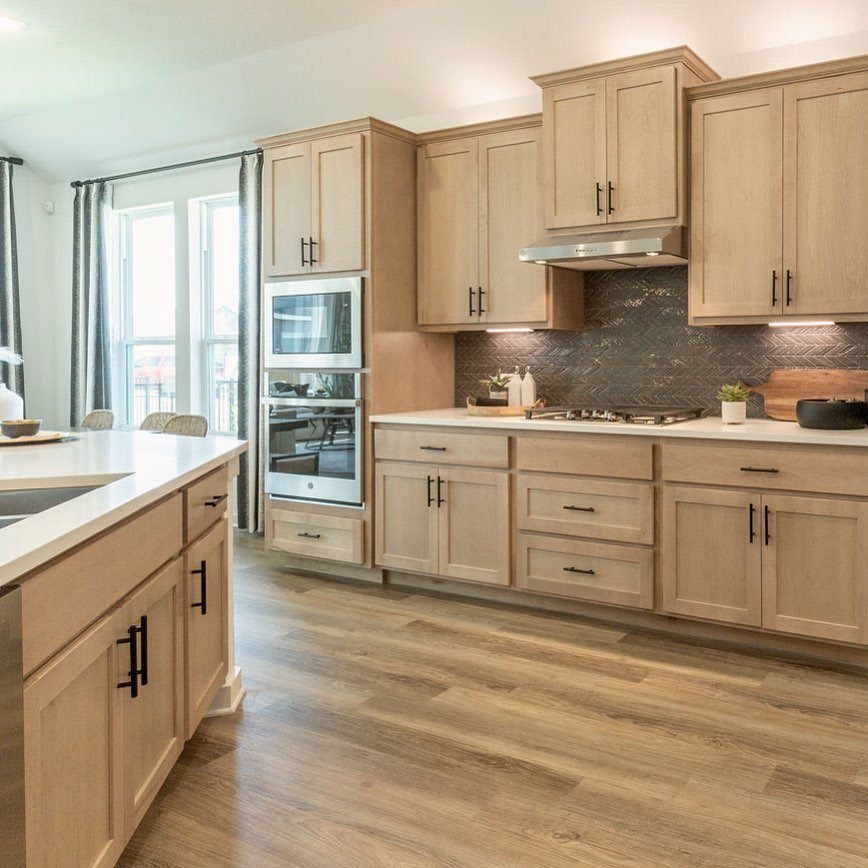 Light Wood Flooring: 10 Ideas That Actually Work 2 Light wood flooring installed in a modern kitchen with light wood cabinets and white countertops.