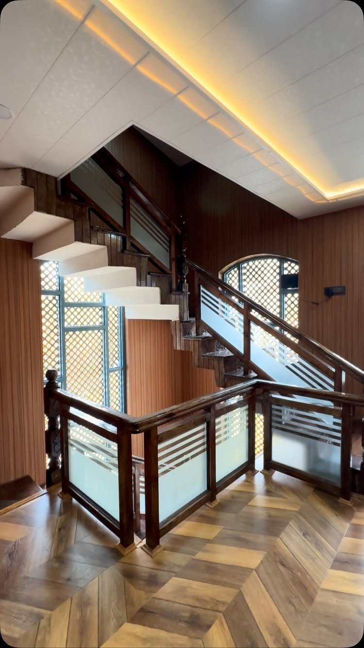 Light wooden parquet flooring in a geometric pattern on a staircase landing with dark wood railings.