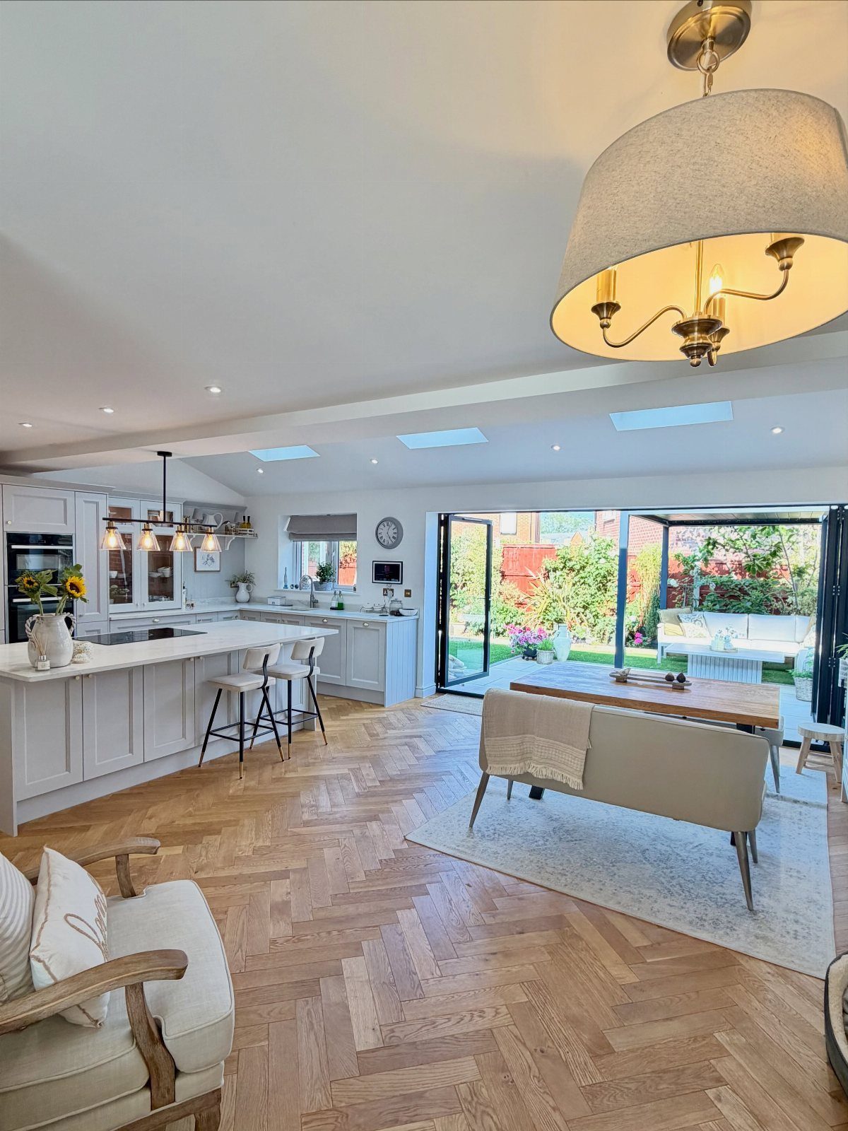 Light wooden herringbone flooring in a bright, modern open-plan kitchen and dining room.