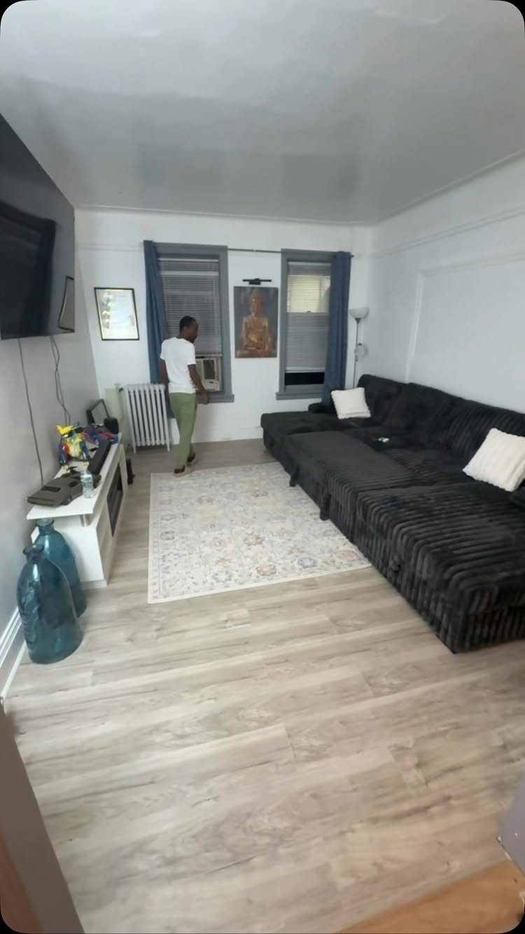 Light gray wood-look laminate flooring in a living room with a dark sectional sofa.