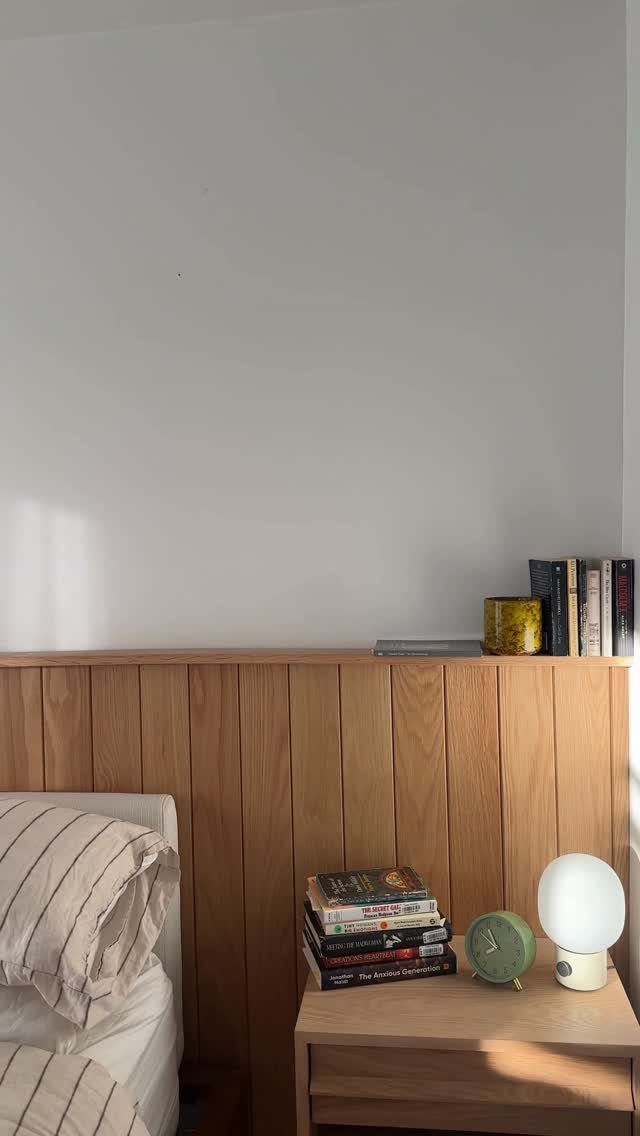 Vertical light wood wall paneling installed on the lower half of a white bedroom wall.
